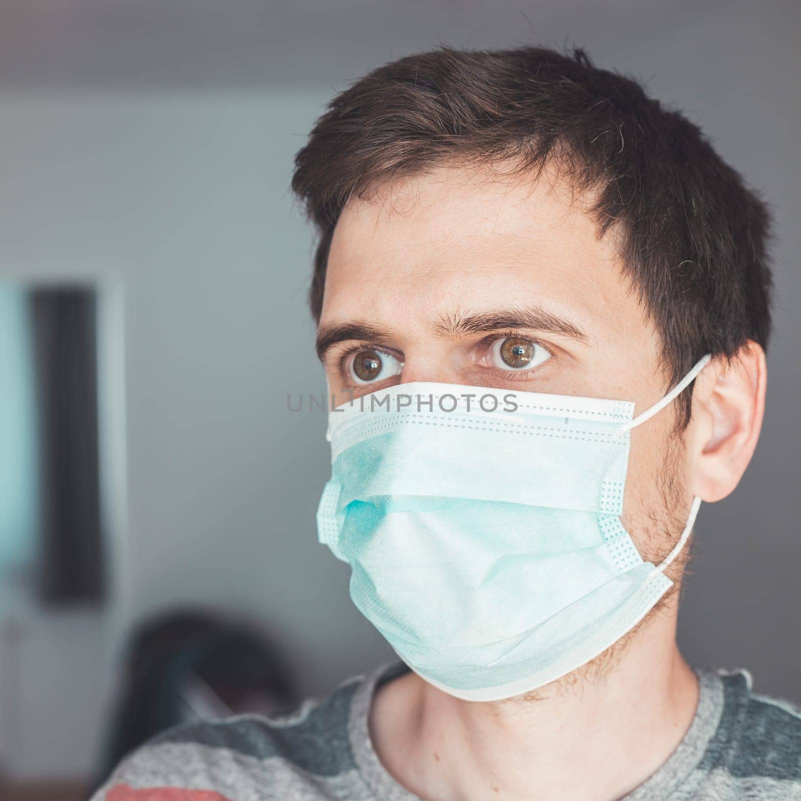 Young man indoor wearing a face mask, portrait. Corona and flu season.