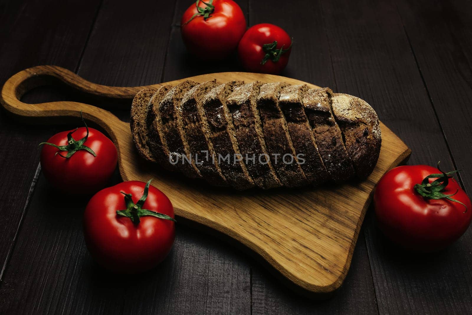 Fresh baked bread and tomatoes on wooden table. High quality photo