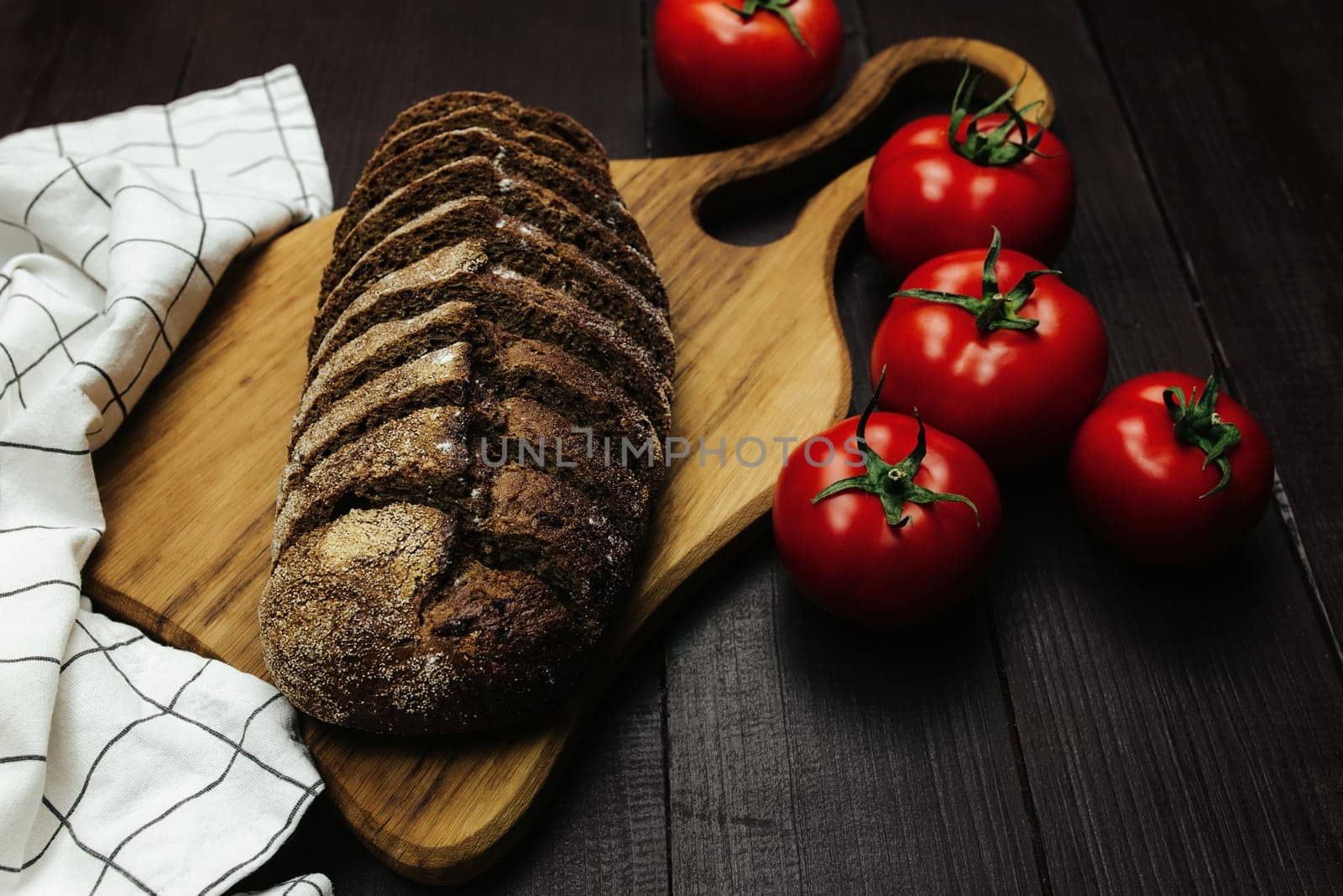 Fresh baked bread and tomatoes on wooden table. High quality photo
