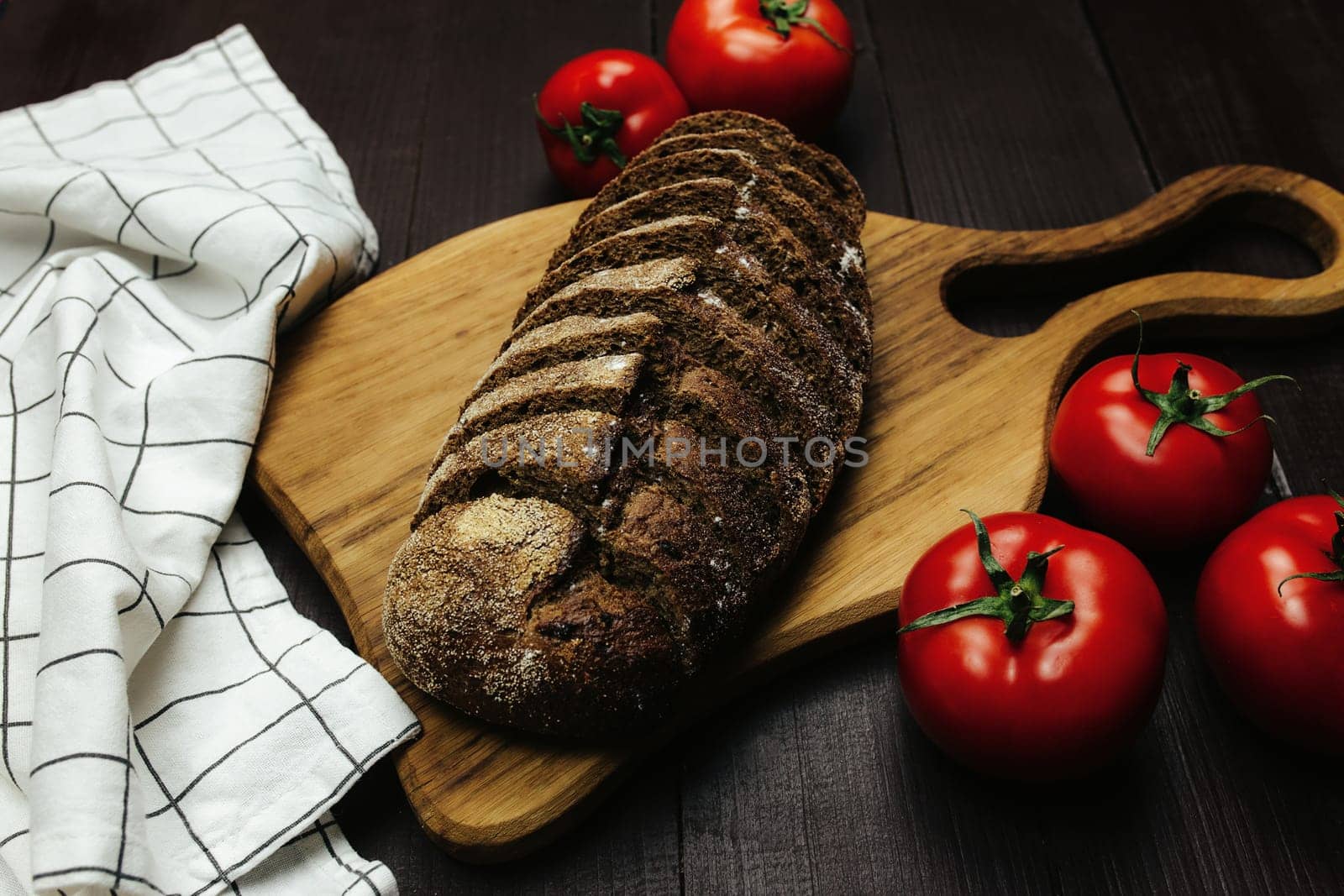 Fresh baked bread and tomatoes on wooden table. High quality photo