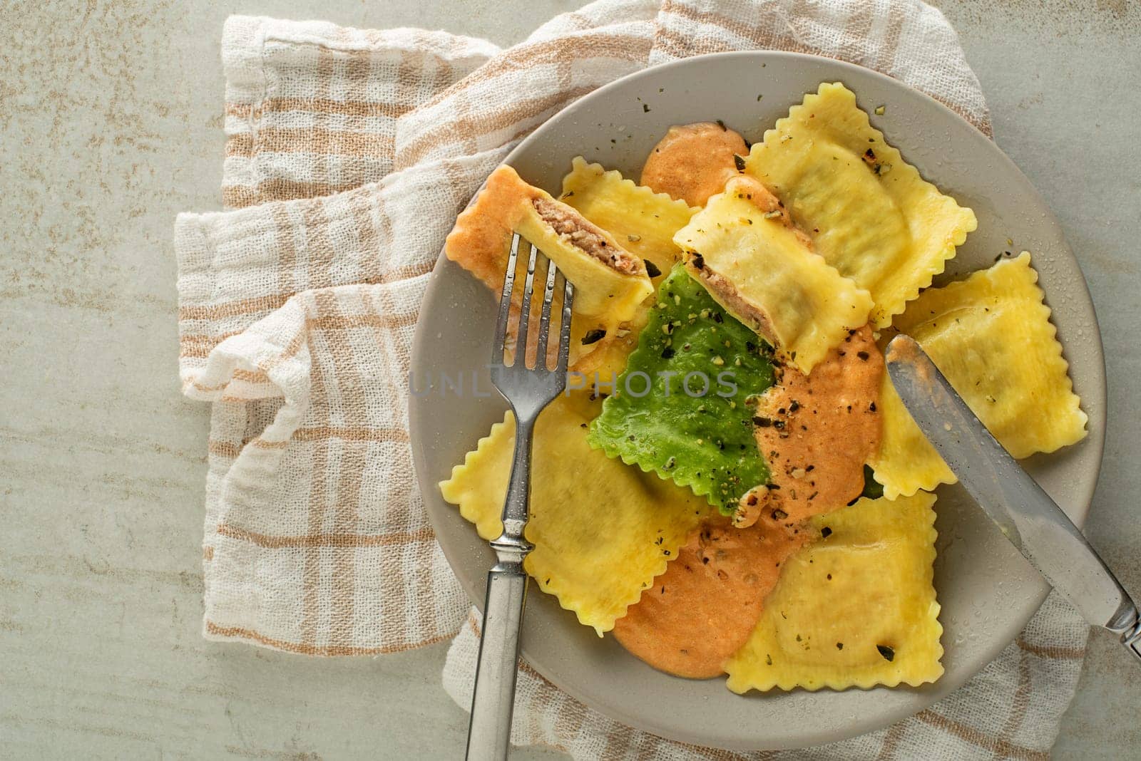Ravioli pasta served with vegetable sauce close up. Small pasta envelopes containing ground meat, cheese and vegetables
