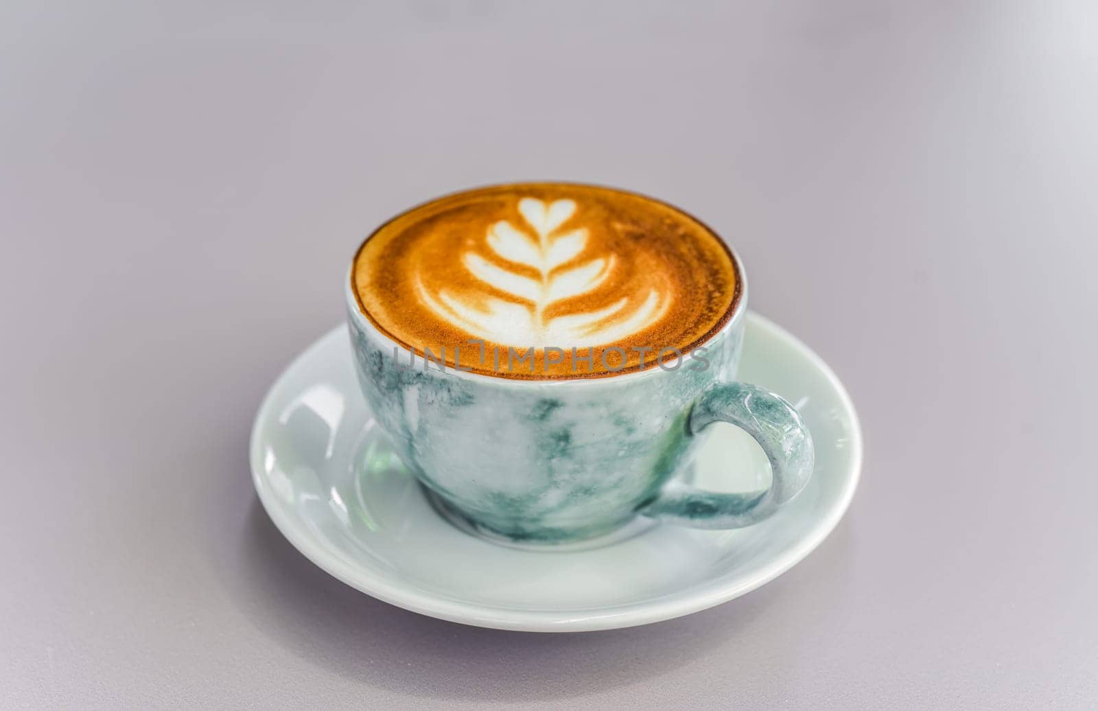 Cup of cappuccino with drawing on light gray background top view