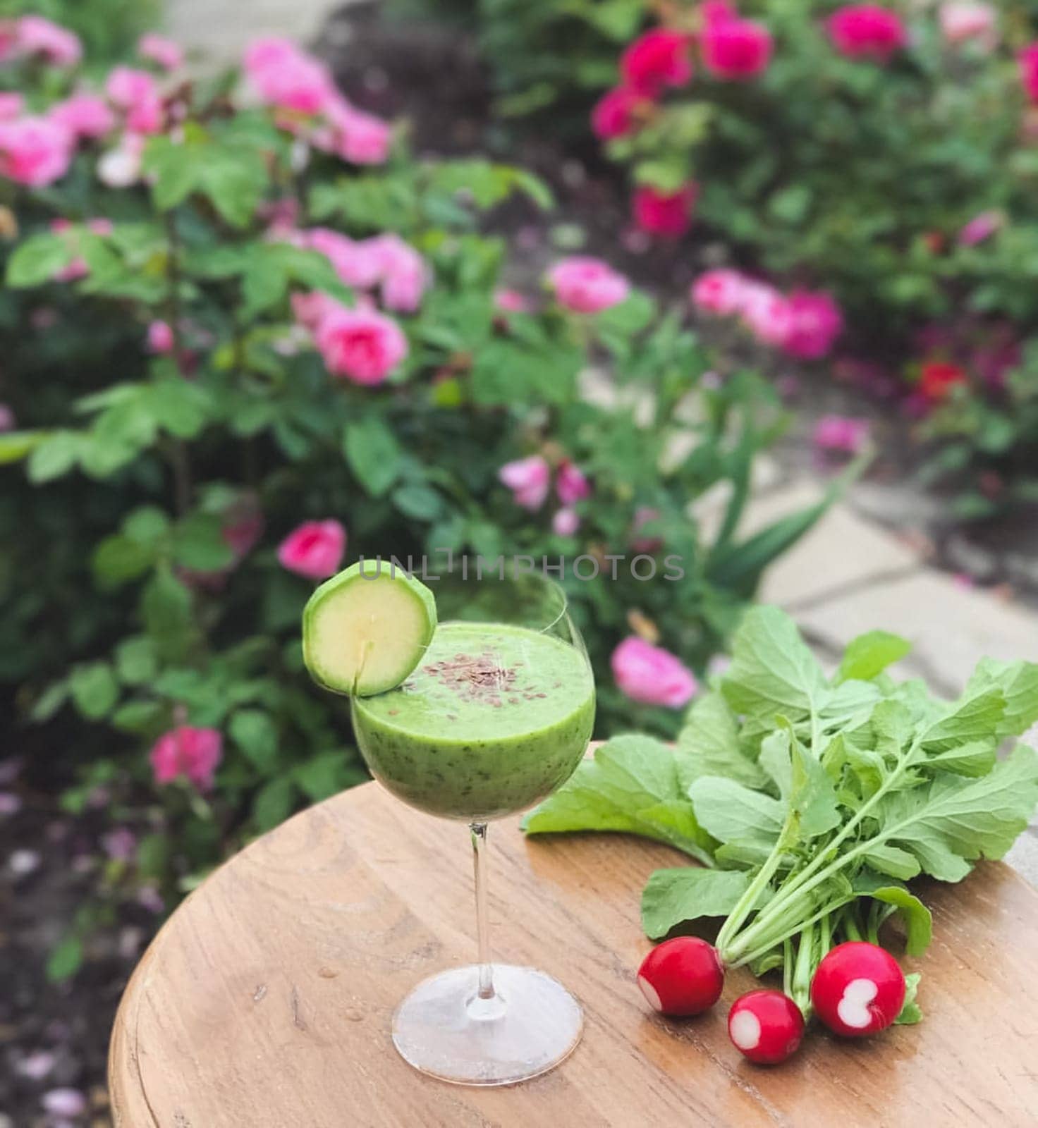 A glass of vegetable juice on the table. A bunch of radishes.
