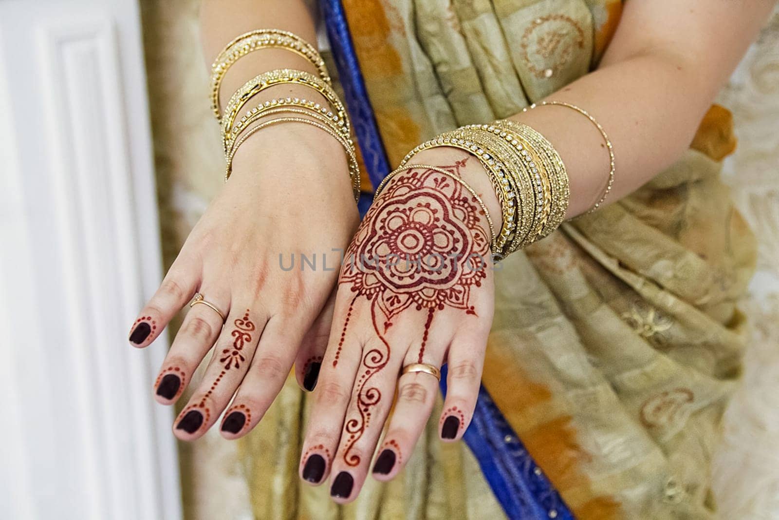 Indian woman's hands in gold bracelets and tattoos.