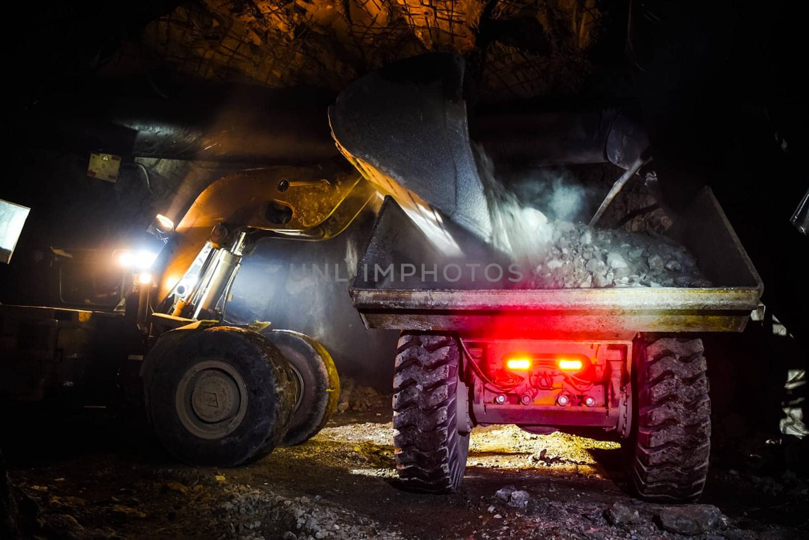 Loading the rock with a bulldozer into a dump truck. Work in the mine.
