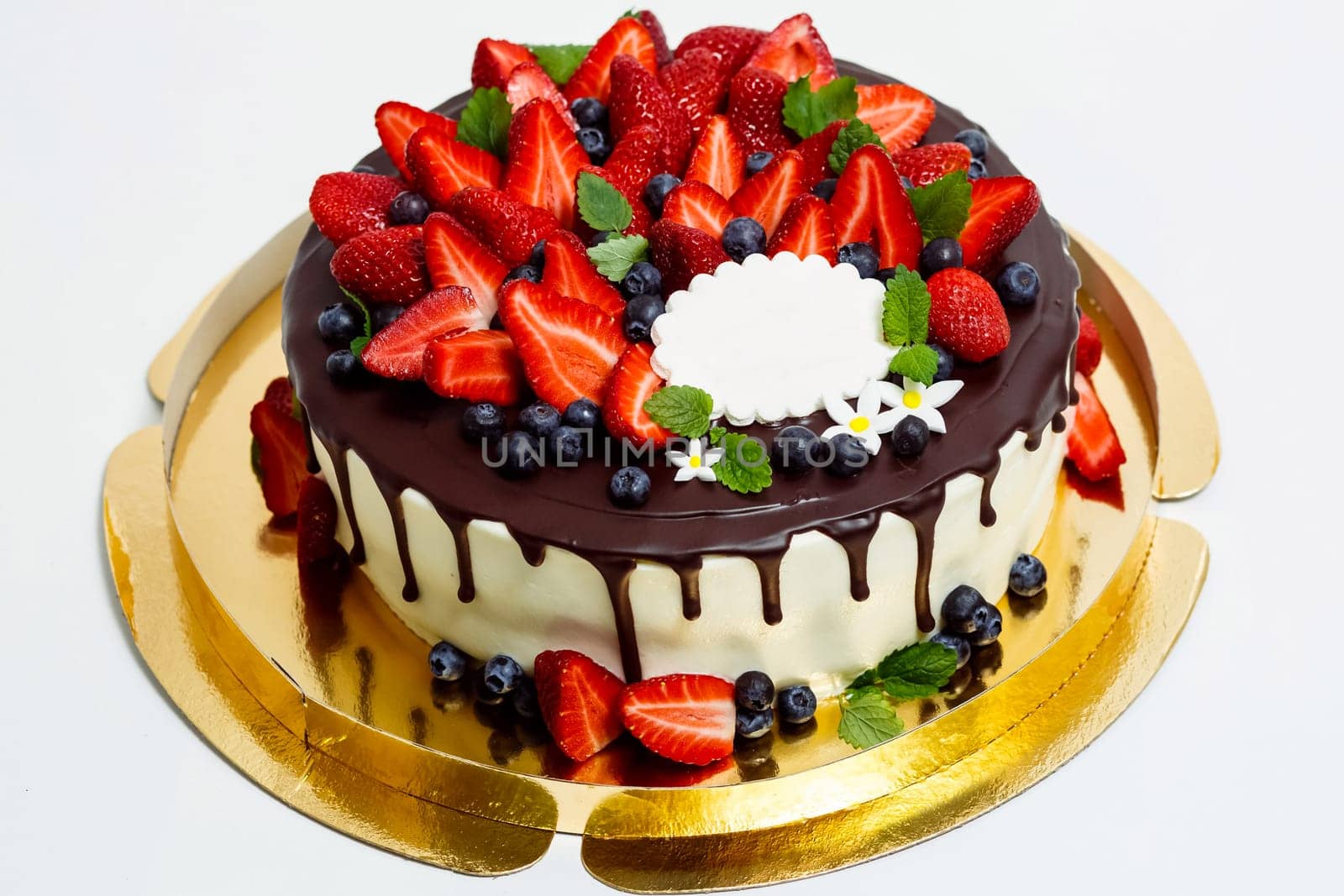 Cake in chocolate glaze and with blueberries and strawberries.