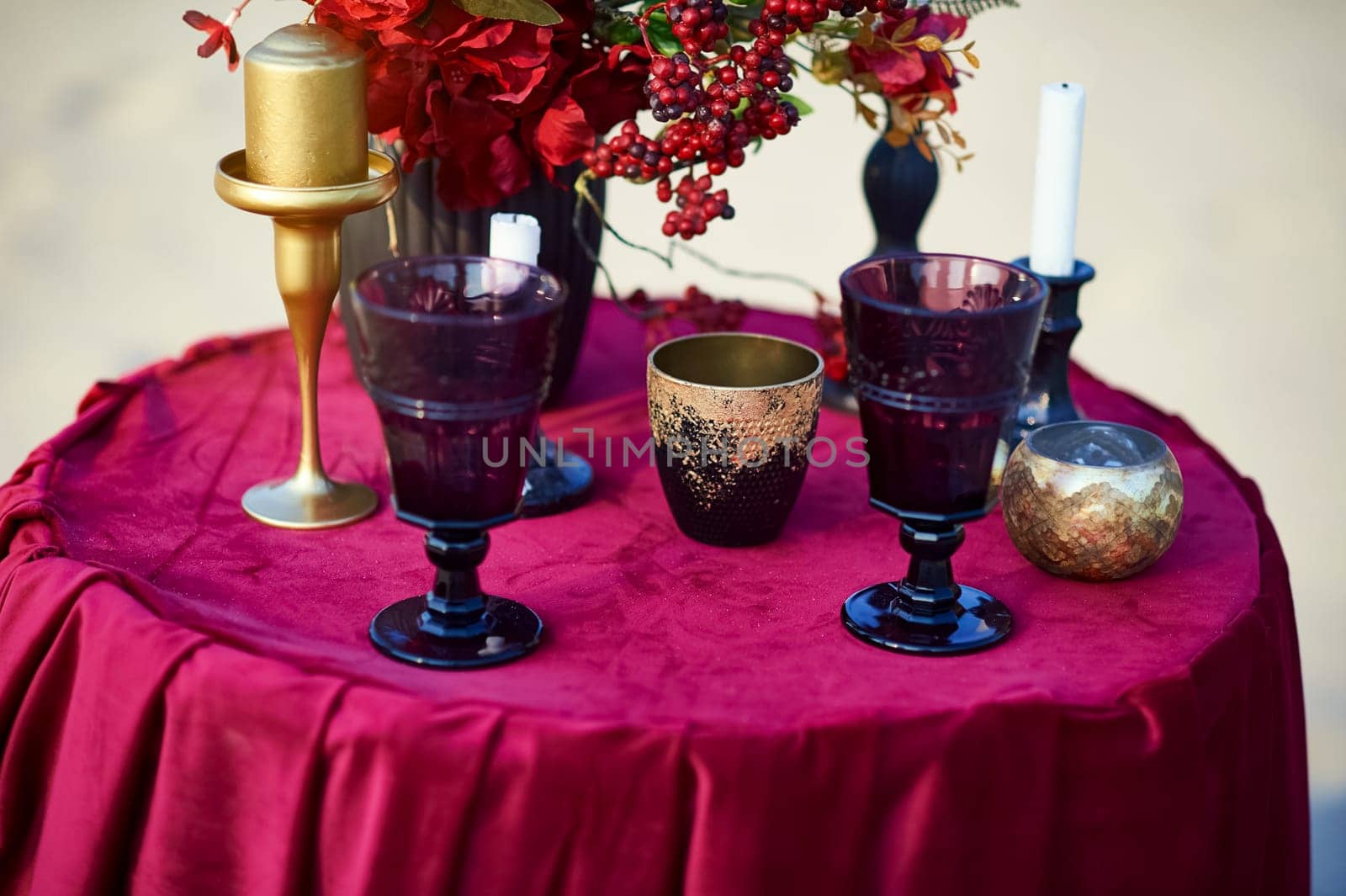 Wine glasses and candlesticks on the red table.