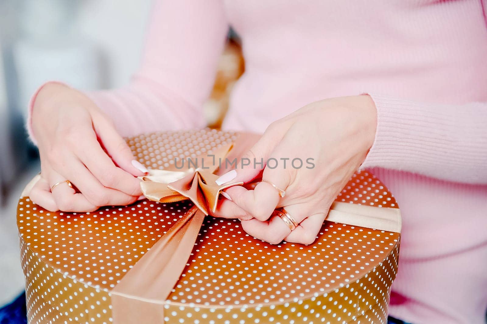 A woman ties a box with a gift. Gift packaging.