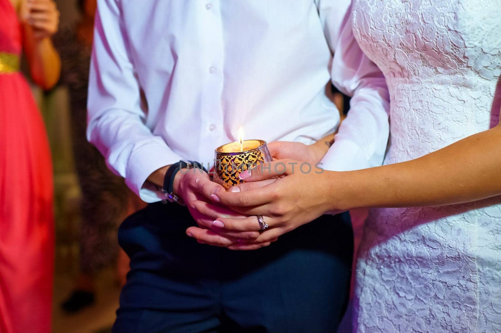 The bride and groom hold the glass together. The newlyweds hold hands.