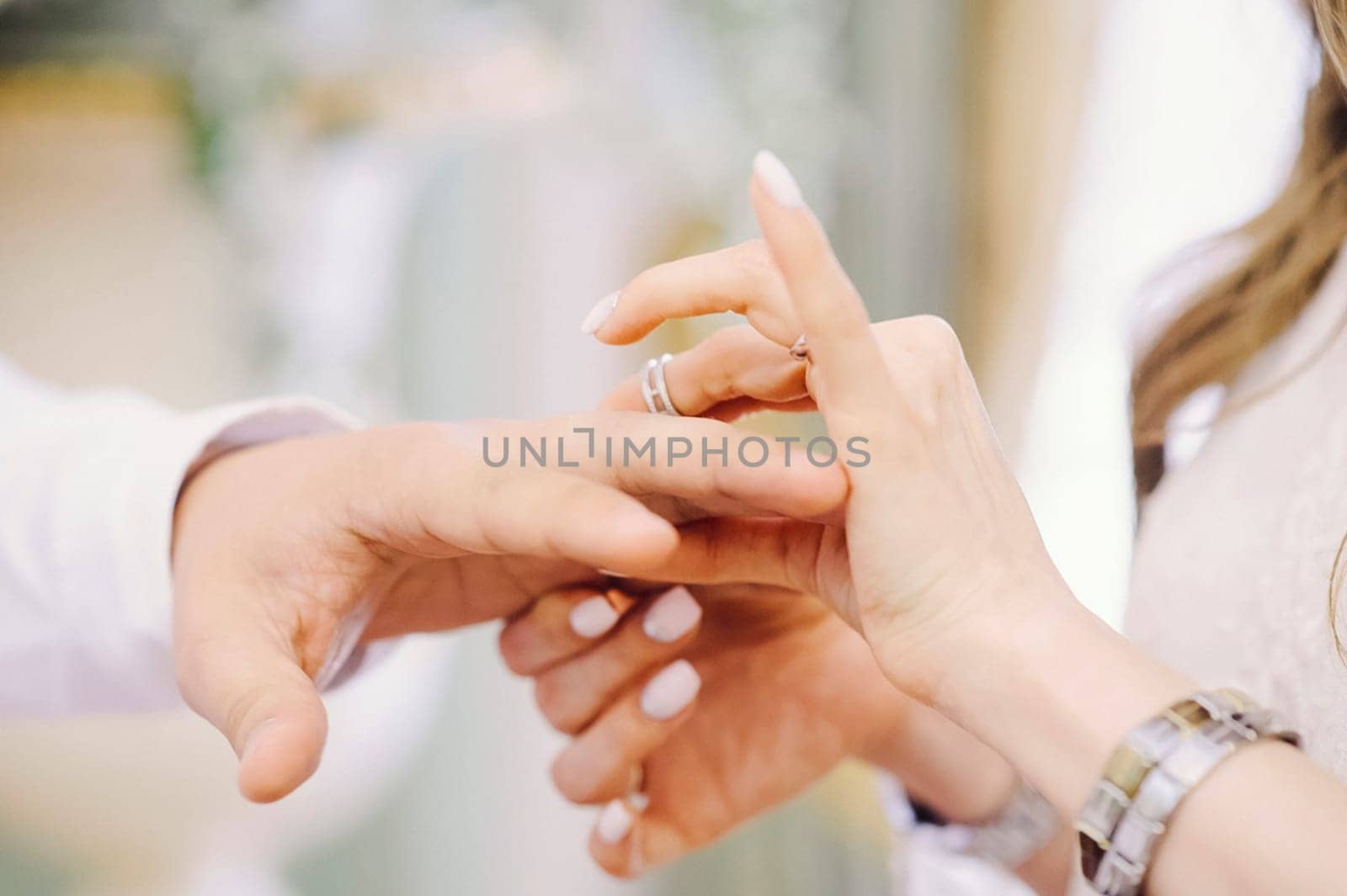 The bride puts the groom's ring on her finger. Wedding