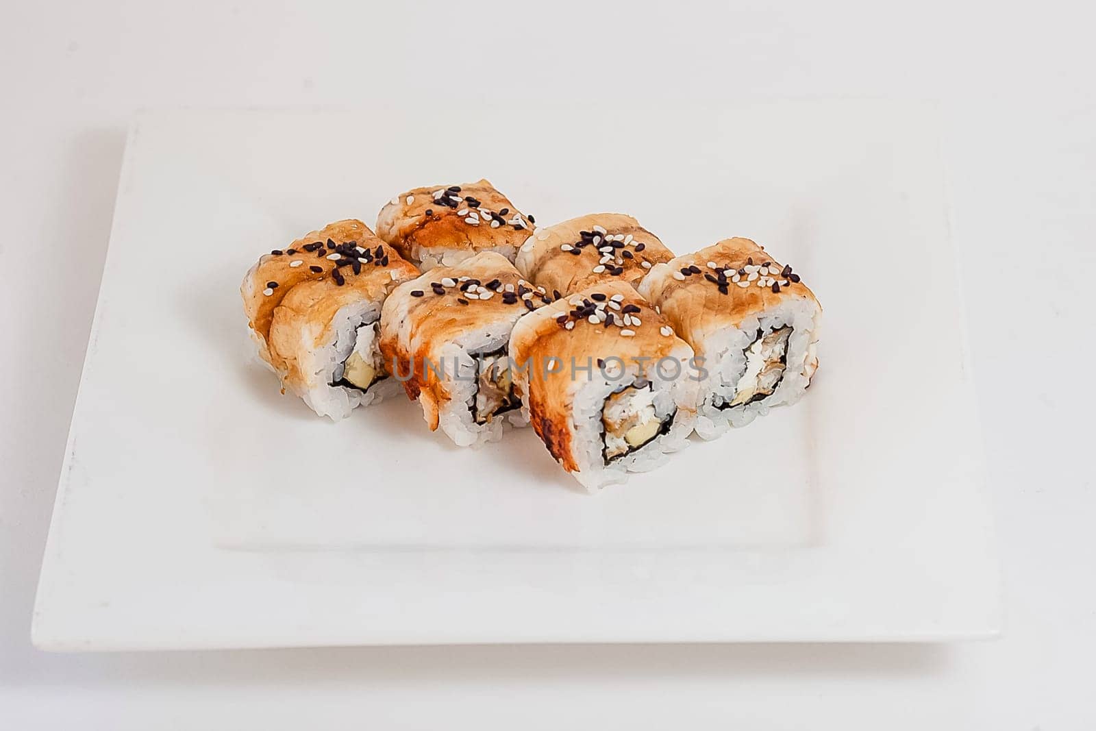 Rolls with red fish and rice on the table in a white plate.