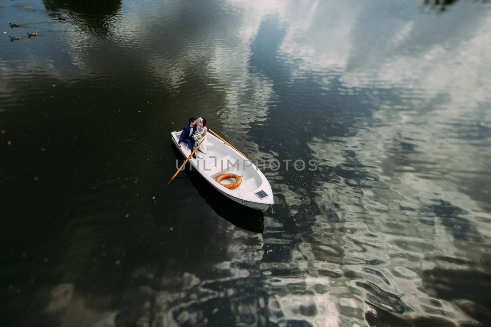 Newlyweds on a white boat swim in the lake.