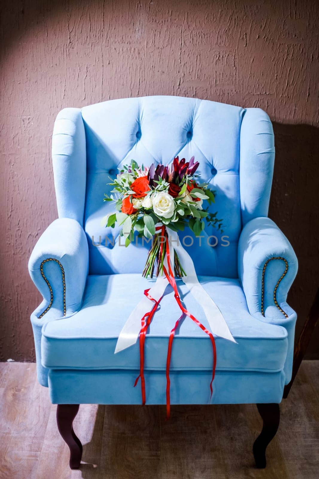A beautiful bouquet of the bride lies on a blue chair.