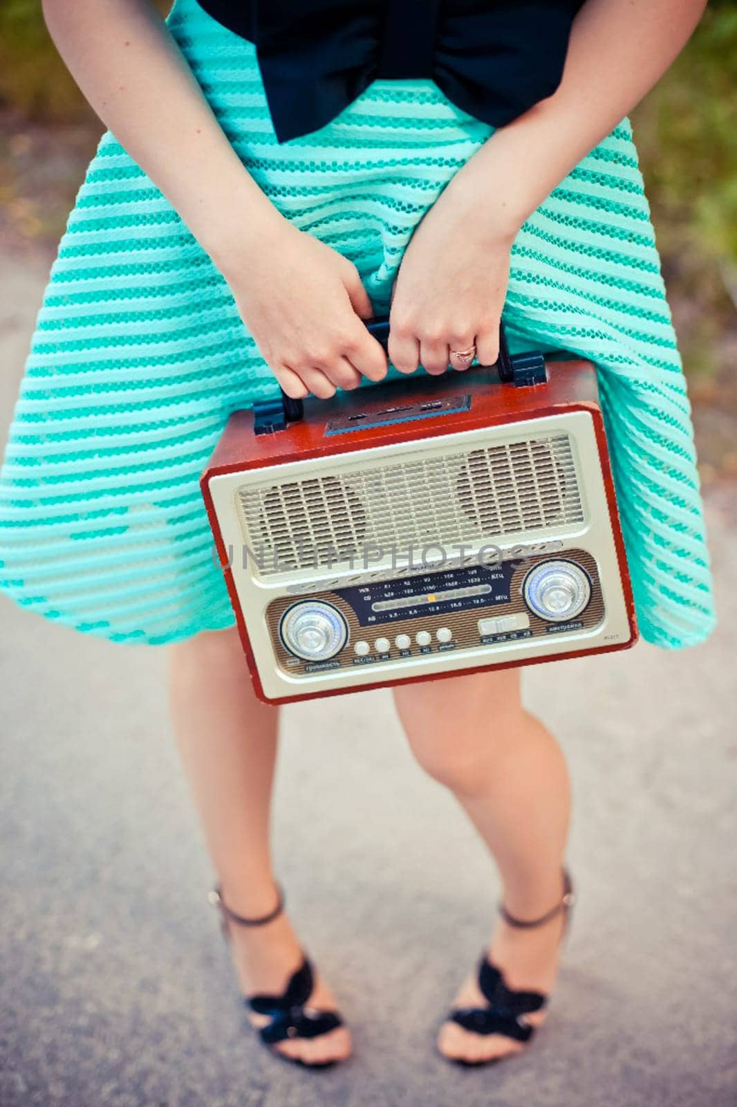 A girl in a dress with a radio in her hand. Retro style.