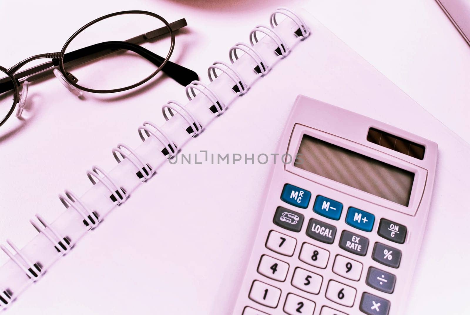 Close_up of a calculator and eyeglasses on a spiral notebook
