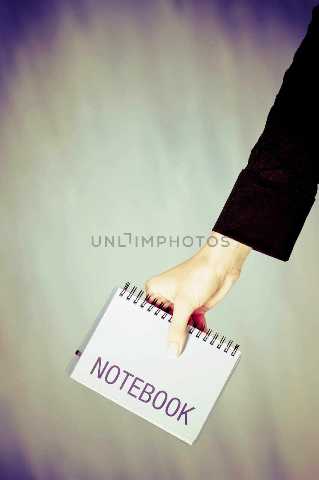 Close_up of a personŽs hand holding a spiral notebook