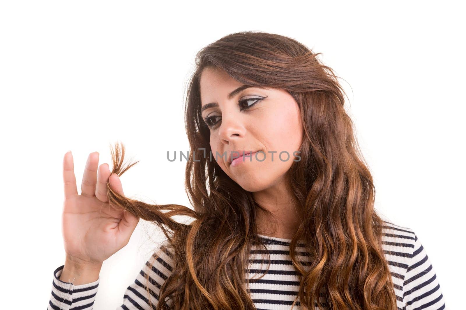 Young woman looking at her hair isolated over white