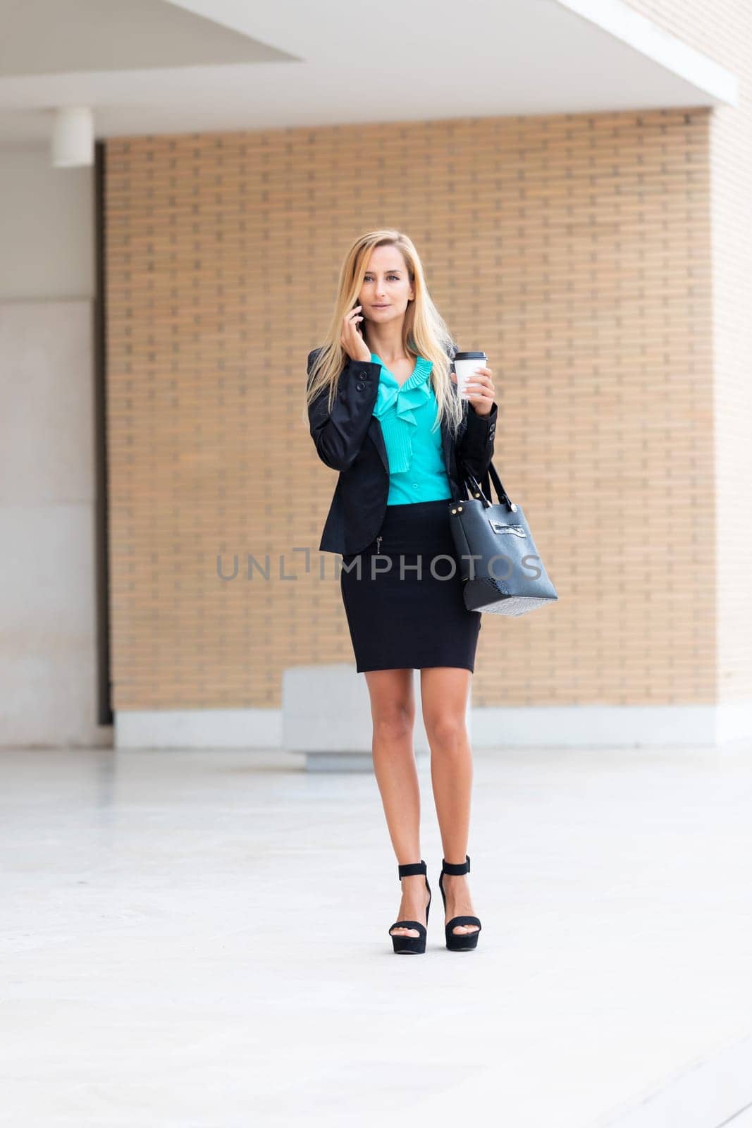 Business woman with coffe and talking on the phone near office