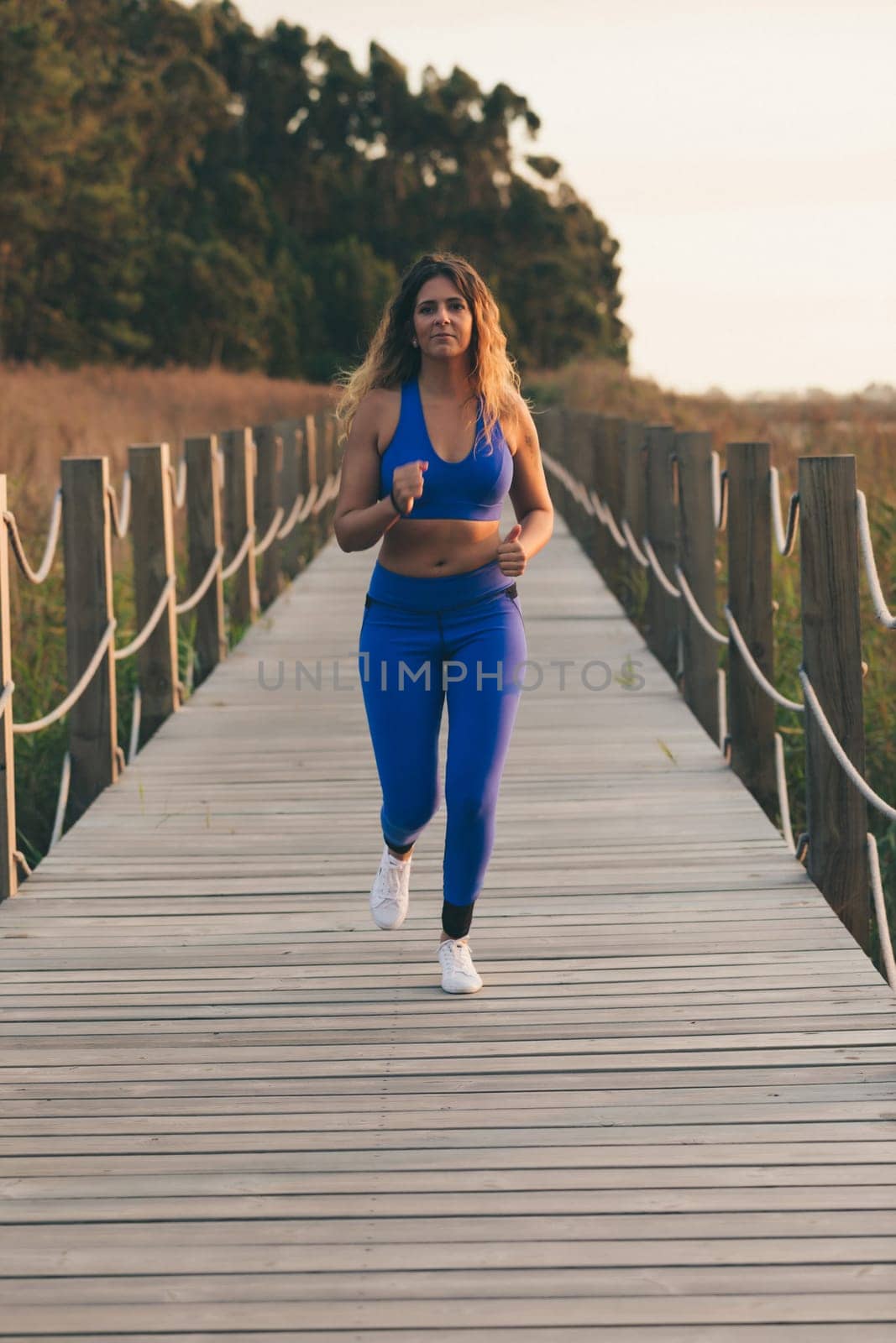Young beautiful sportive girl exercising outdoors during sunrise/sunset
