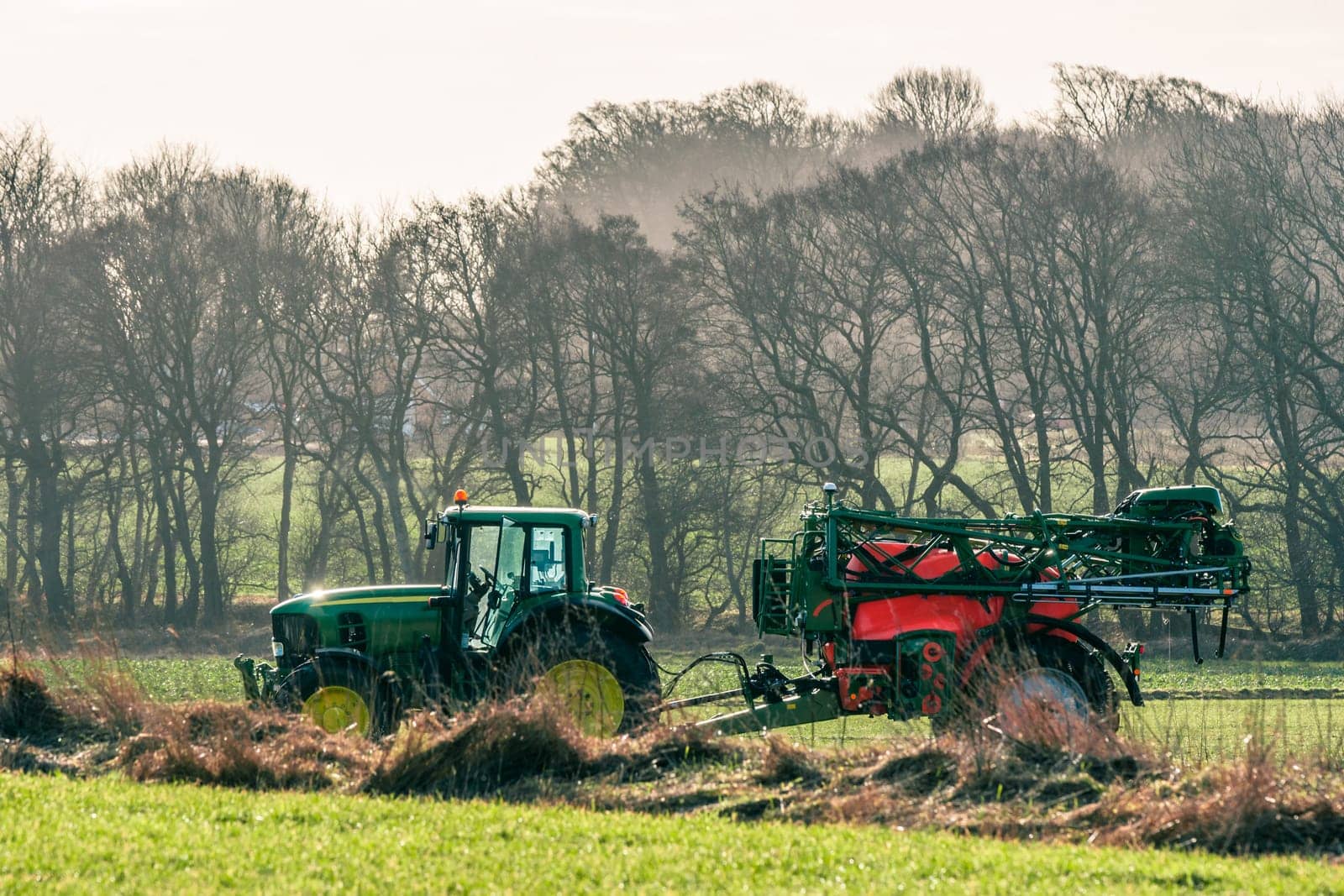 Tractor driving on a field with fertilizer in early spring