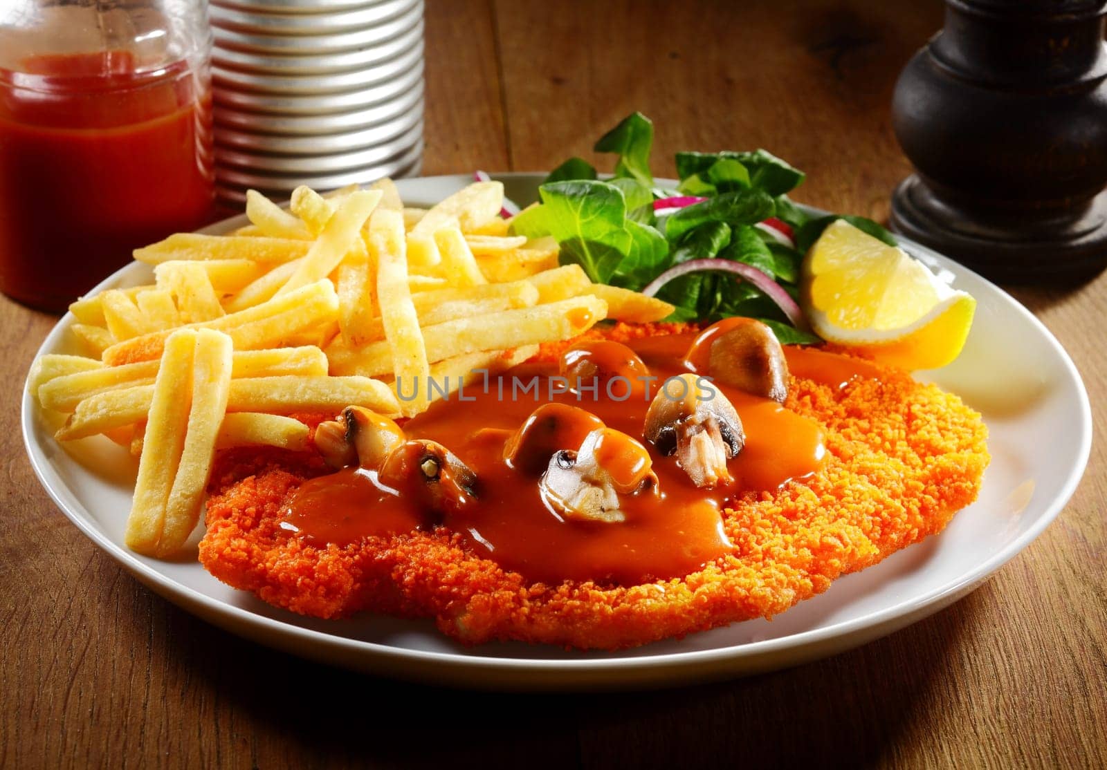 Close up Gourmet Potato Fries and Saucy Escalope on White Plate with Herbs and Lemon.