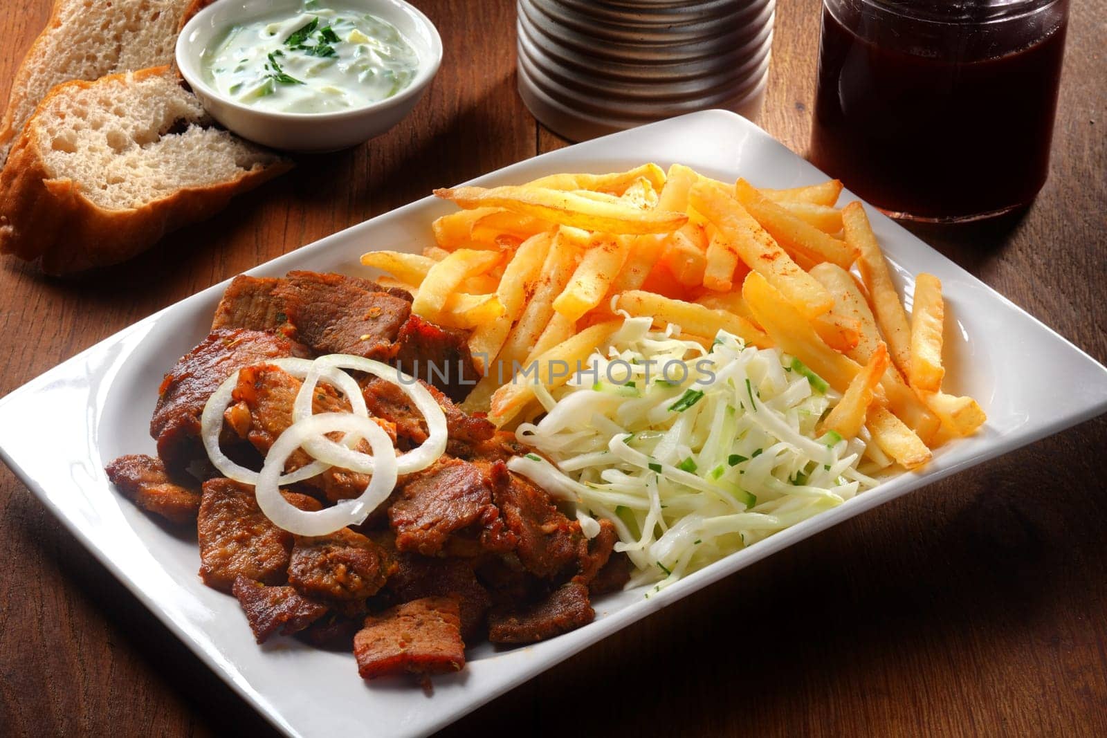 Close up Tasty Gyros, Shredded Cabbage and Potato French Fries on White Plate, Placed on Wooden Table.