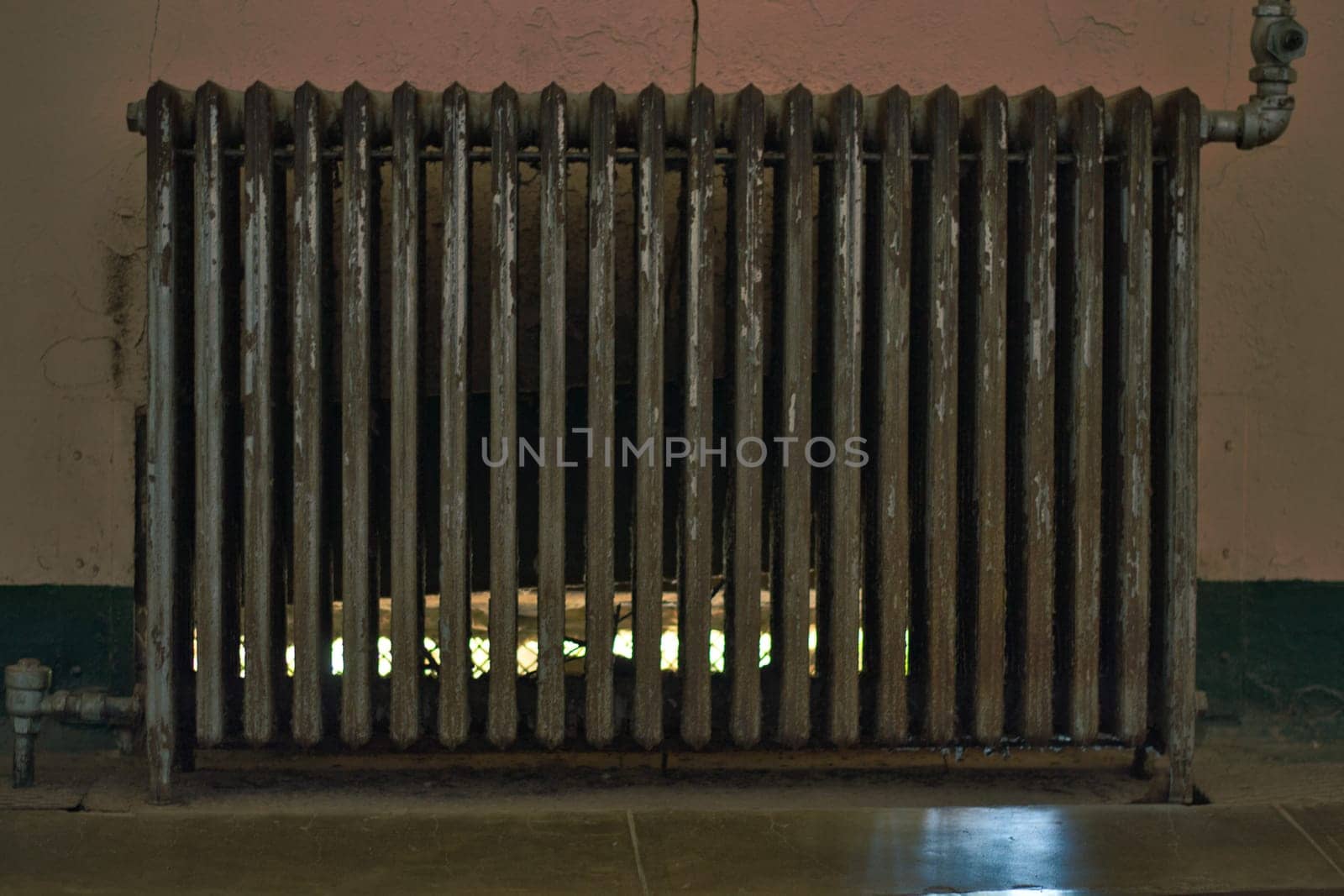 Vintage and retro or old-fashioned heating radiator against a wall. Worn-out and obsolete..