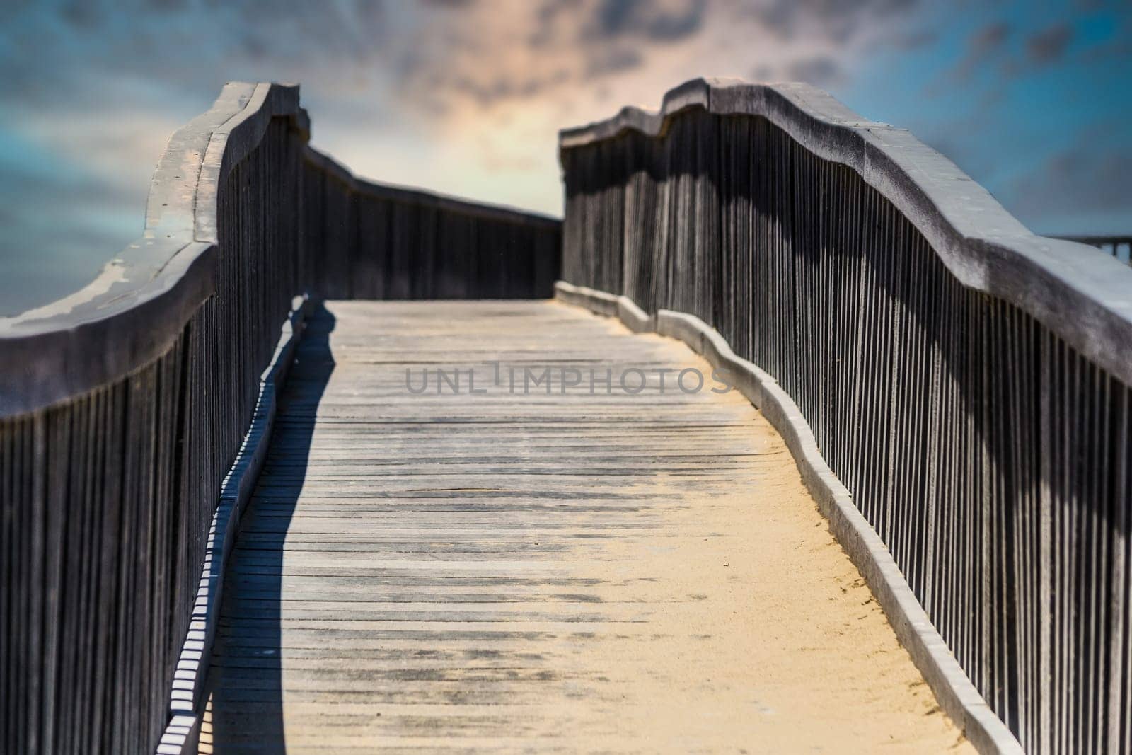 Wooden walkway bridge covered with sand, leading to infinity point.