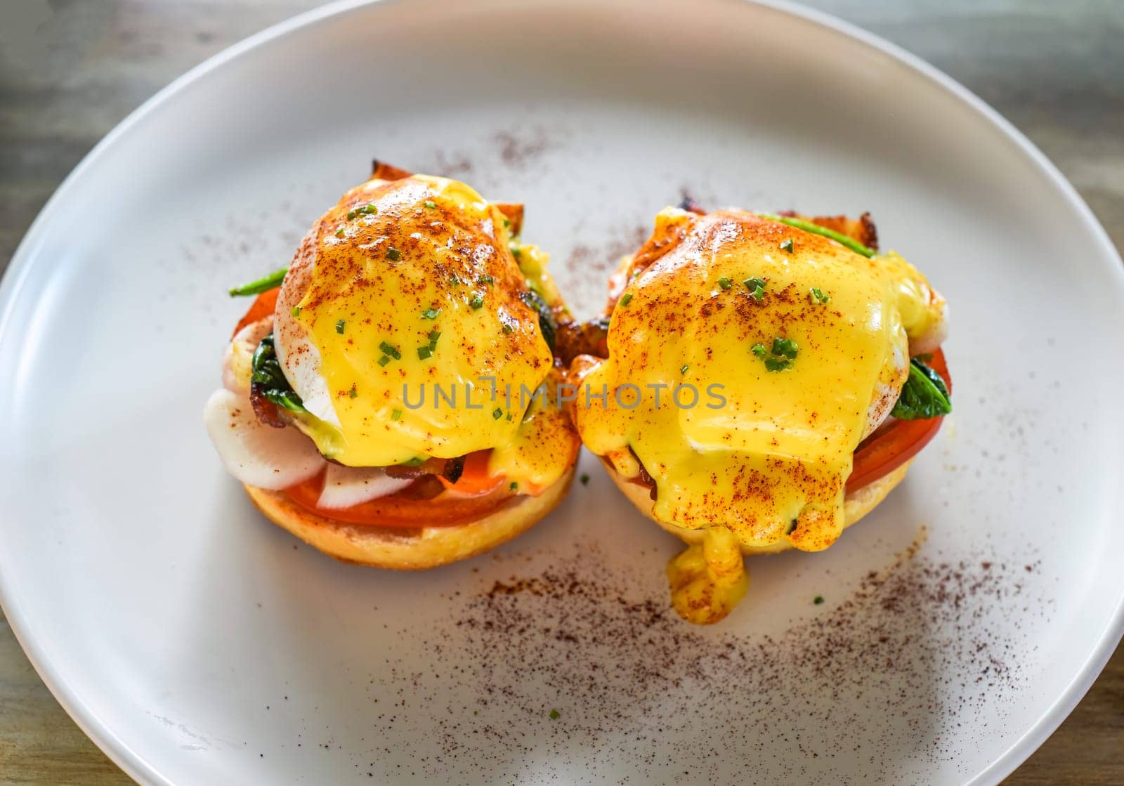 English muffin with poached eggs, bacon and Hollandaise sauce with vegetables