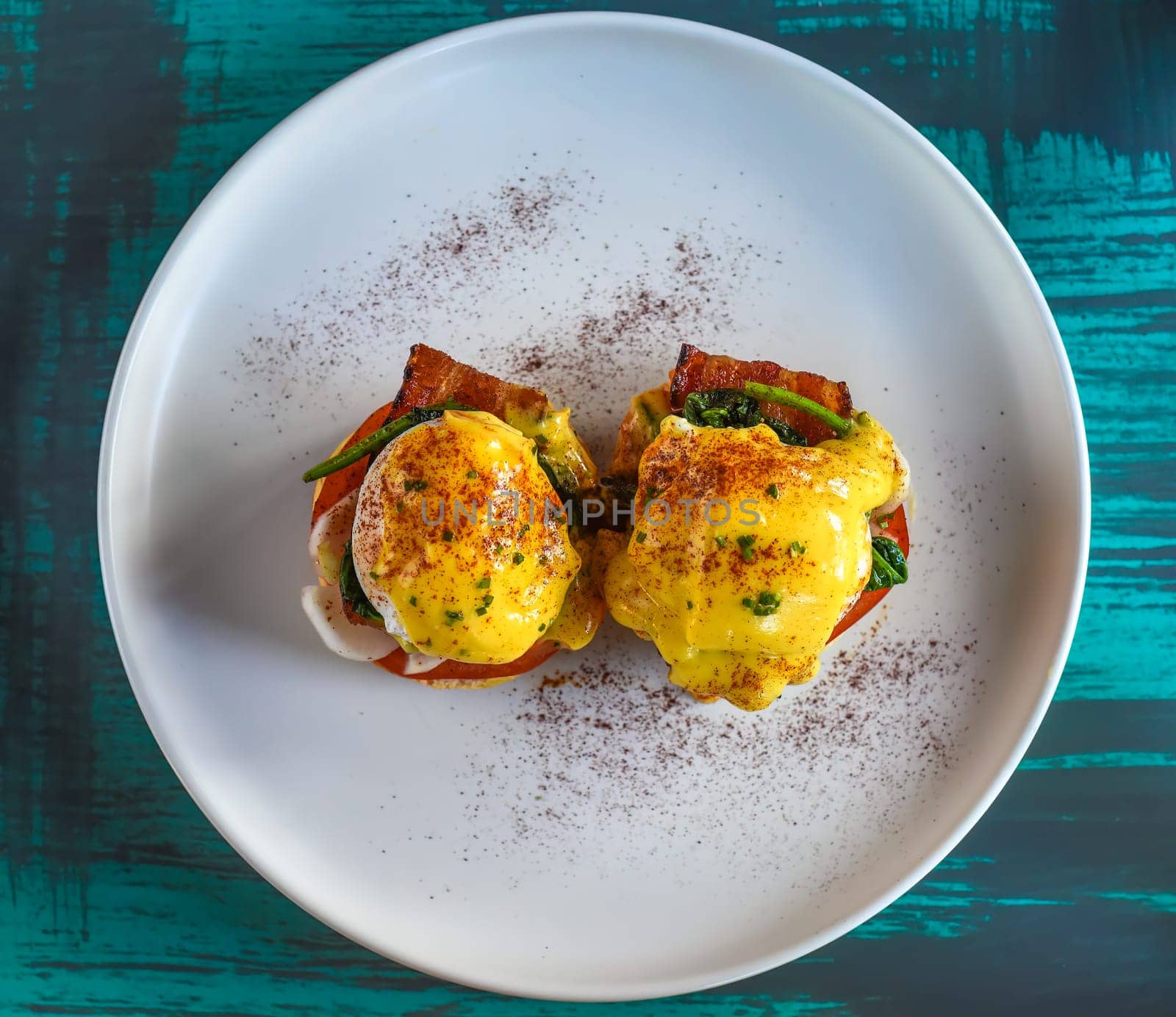 English muffin with poached eggs, bacon and Hollandaise sauce with vegetables