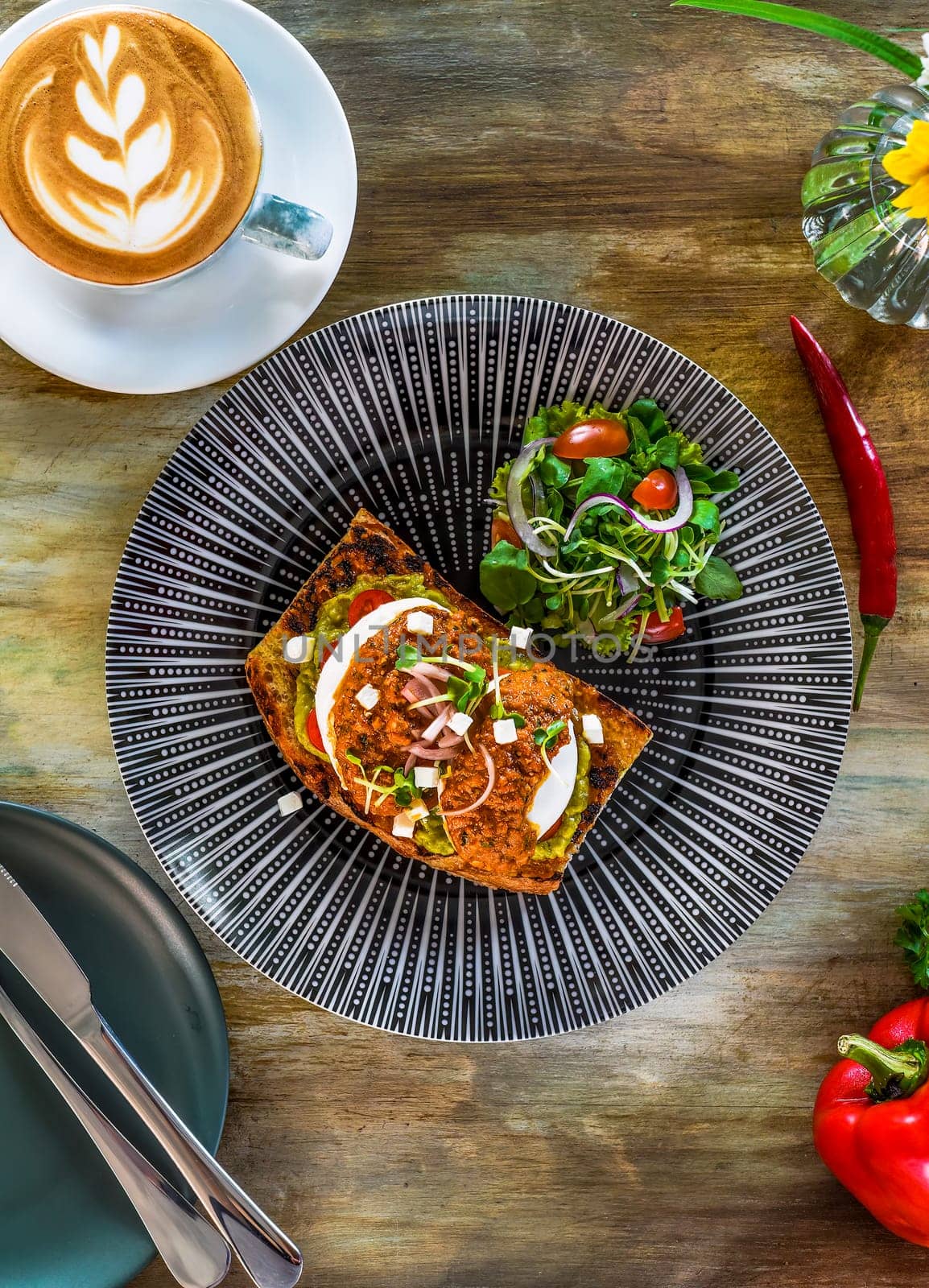 Smashed avocado with poached eggs, red pepper pesto and pickle shallot on toast top view