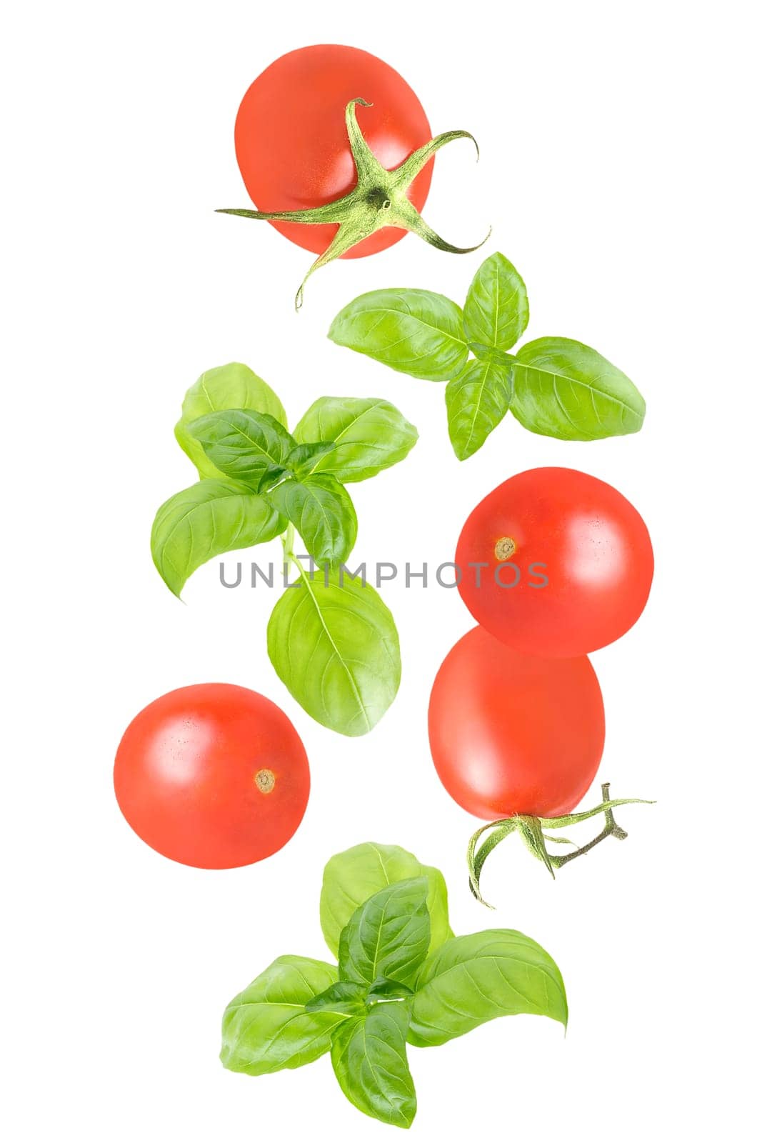 Isolated vegetables in the air. Seven whole tomatoesand basil leaves falling down on white with clipping path as package design element. Full depth of field. Food levitation concept