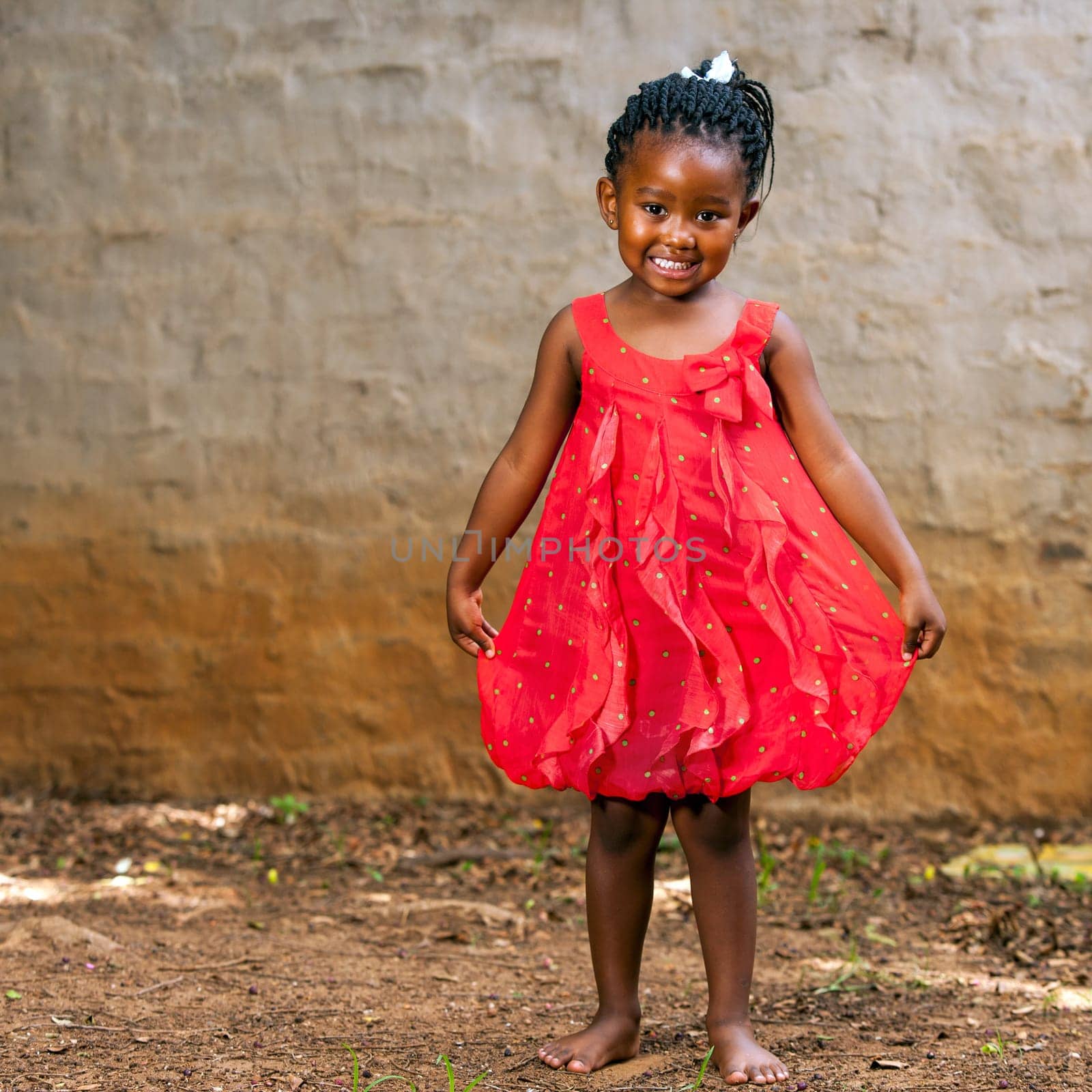 Full length portrait of cute african girl showing red dress outdoors.