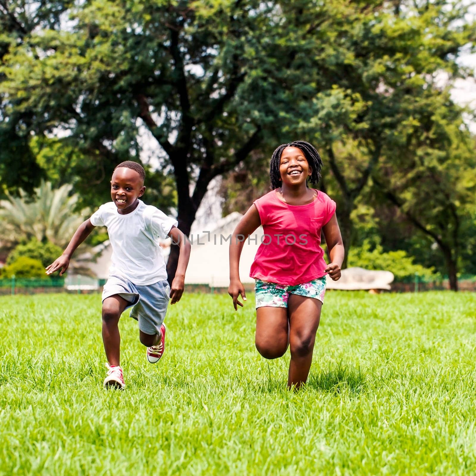 Action portrait of African kids playing and running together in park.
