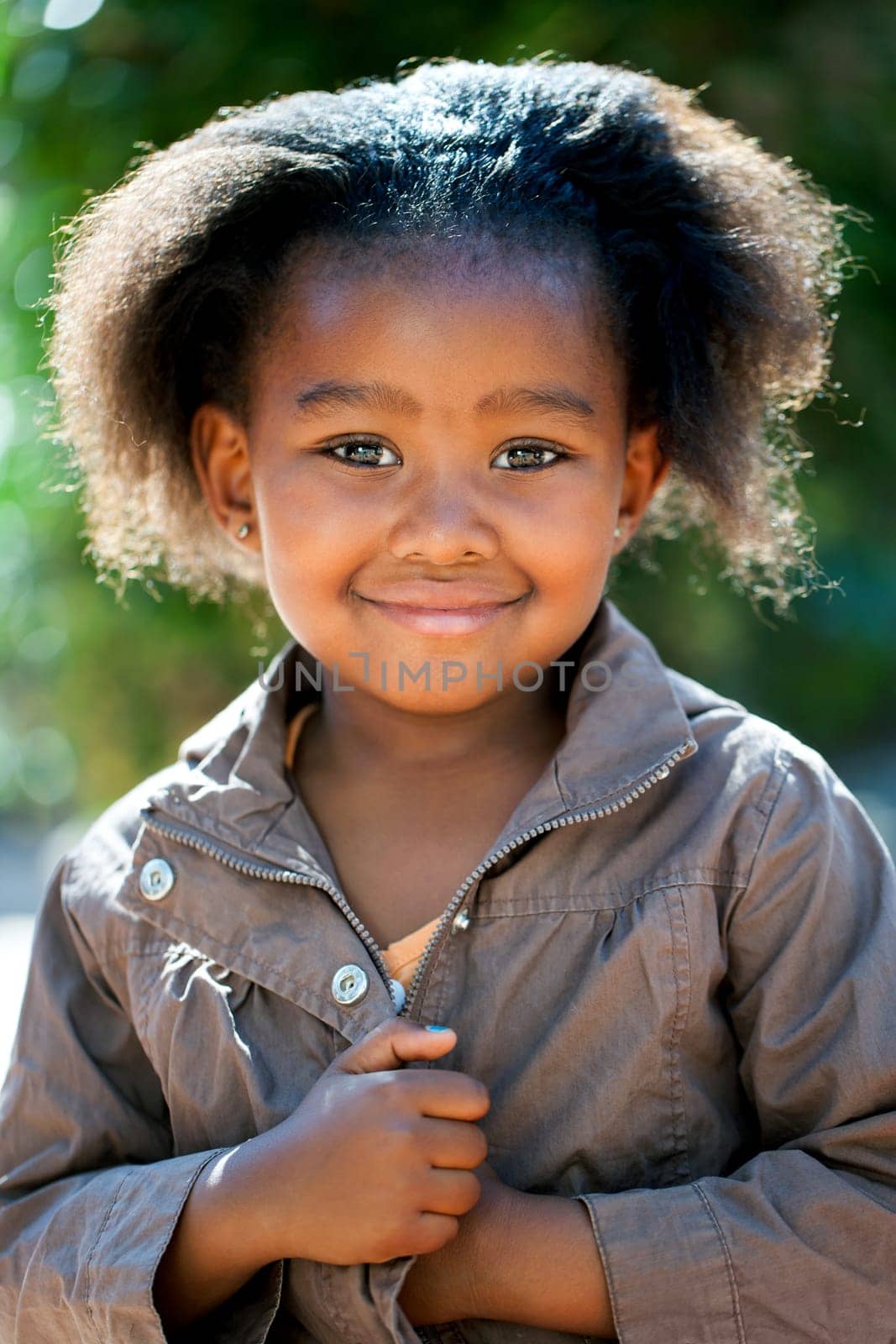 Outdoor portrait of cute African girl wearing brown jacket.