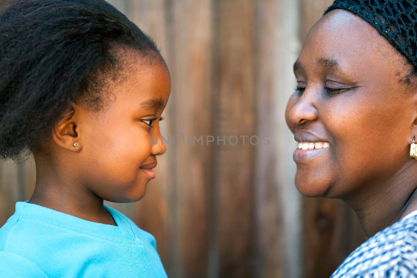 Close up portrait of African mother and daughter looking at each other.