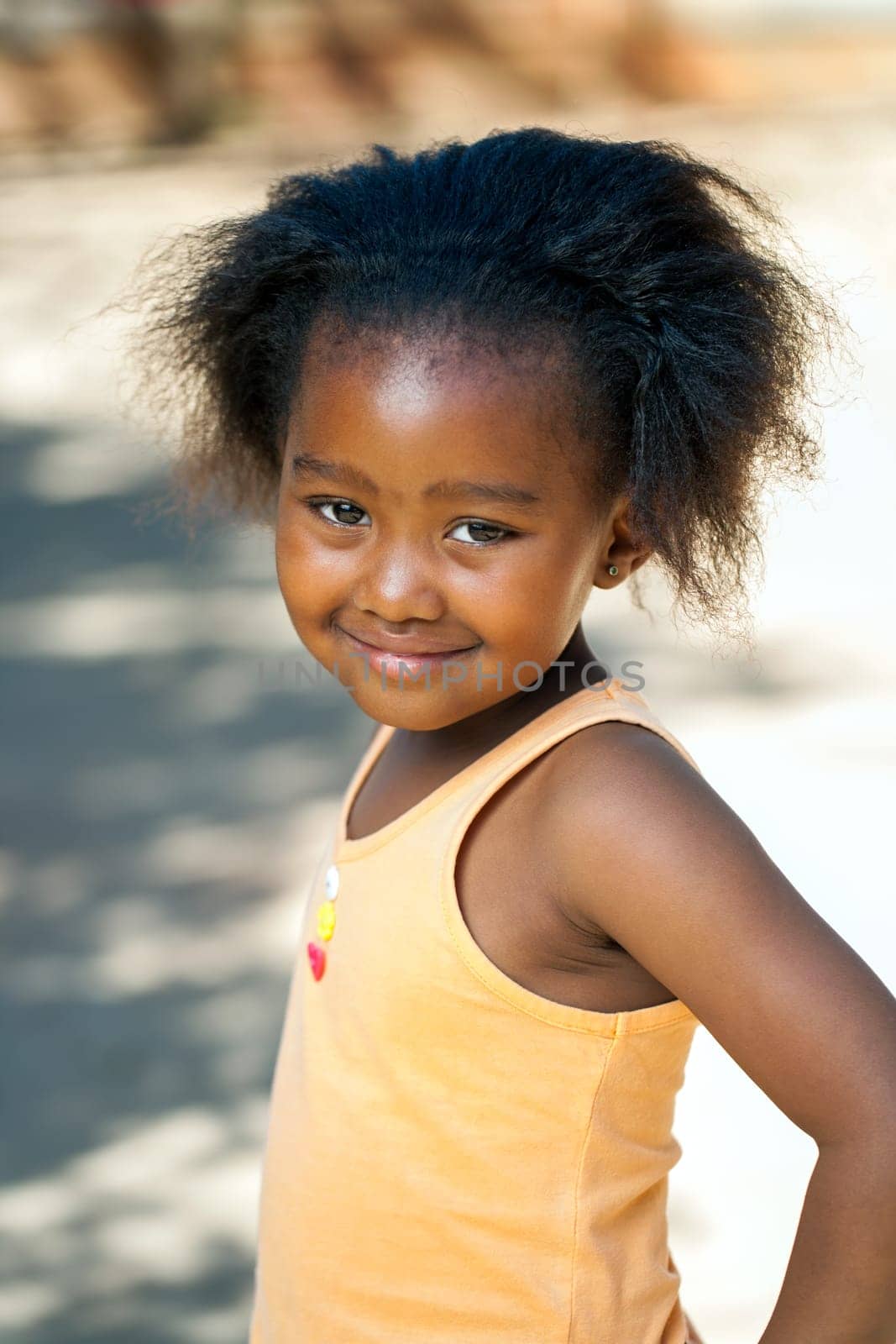 Portrait of cute African youngster in orange vest outdoors.