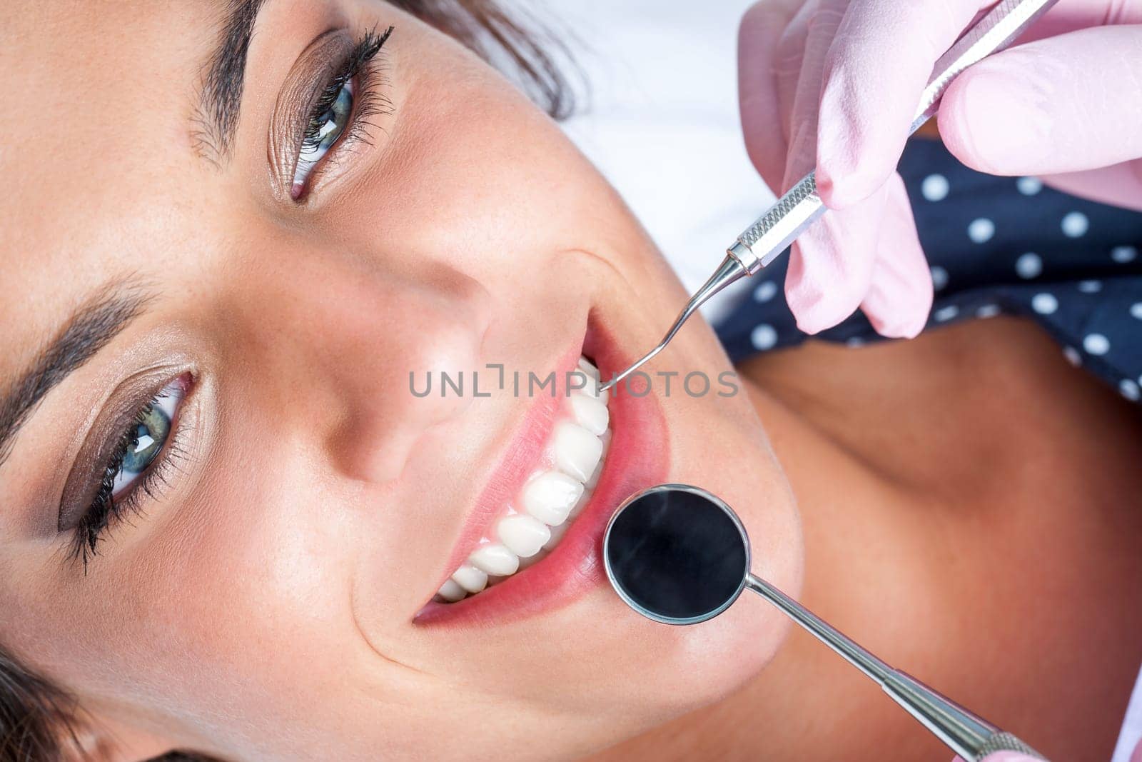 Macro close up of Dentist hands working attractive female teeth.
