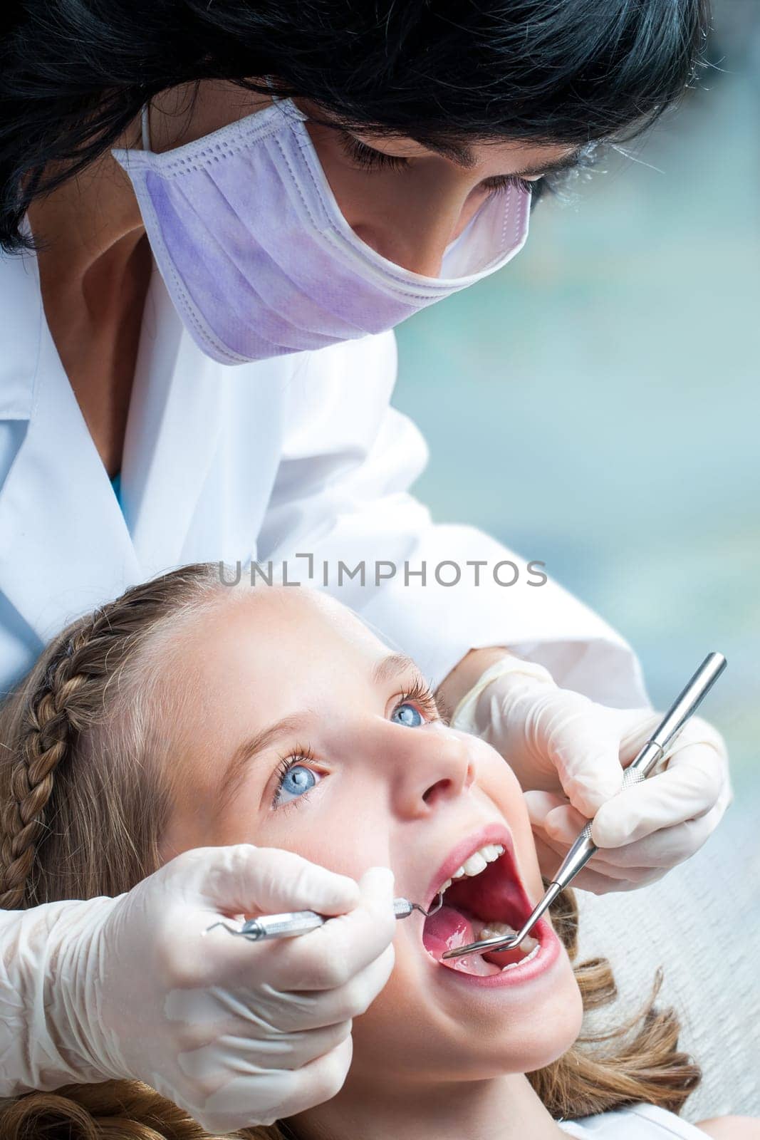 Close up portrait Female Dentist working on little girls teeth.