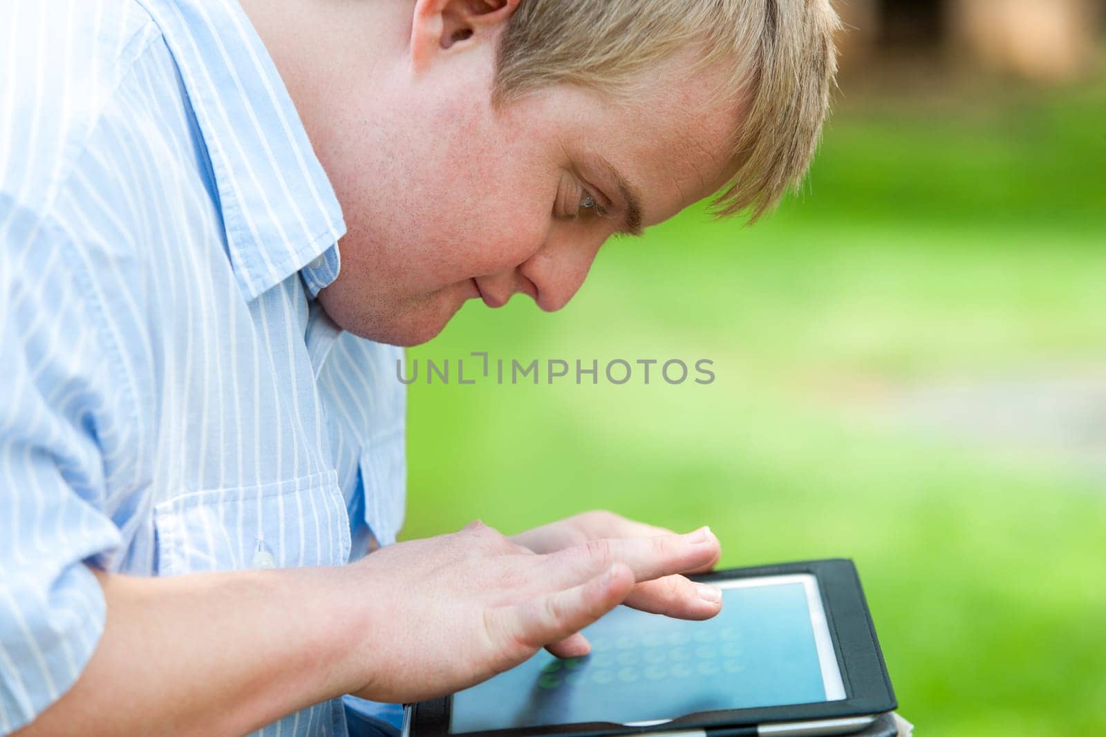 Close up portrait of handicapped boy outdoors with digital tablet.