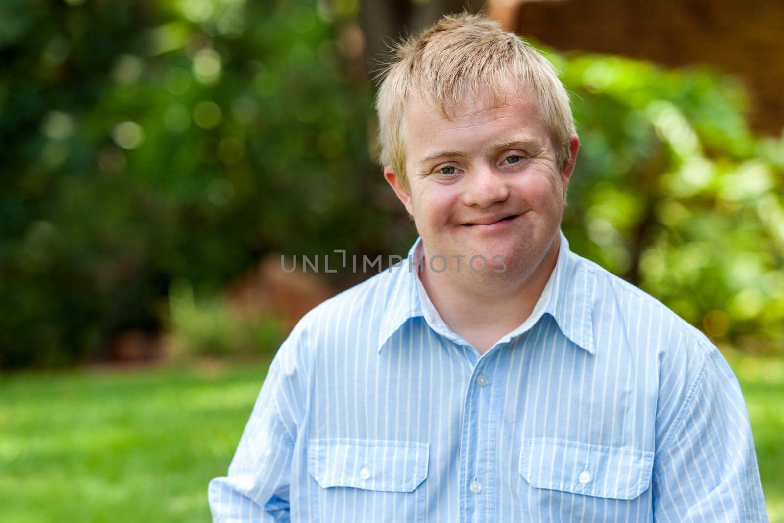 Portrait of handsome handicapped boy in blue shirt outdoors.