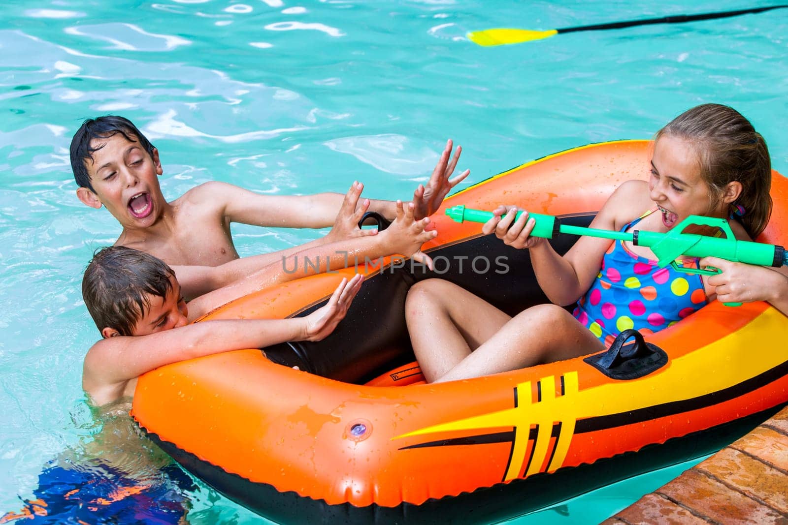 Children in outdoor swimming pool having fun with water games.