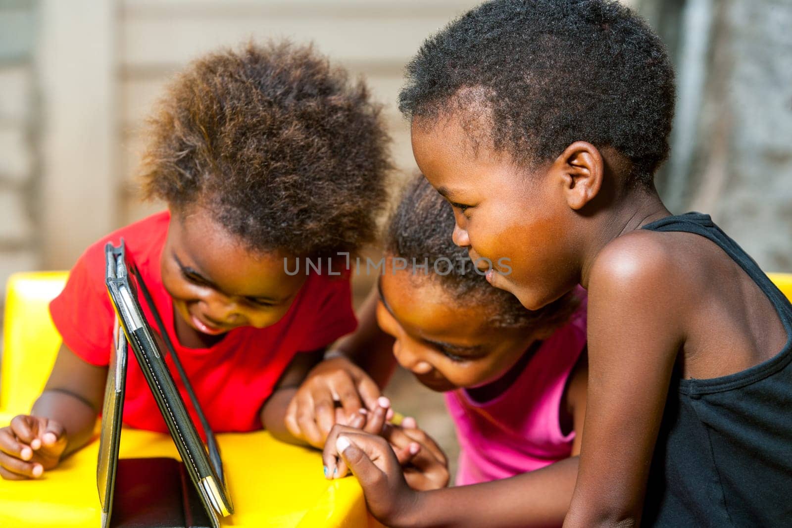Close up portrait of three african young girls playing together on digital tablet.