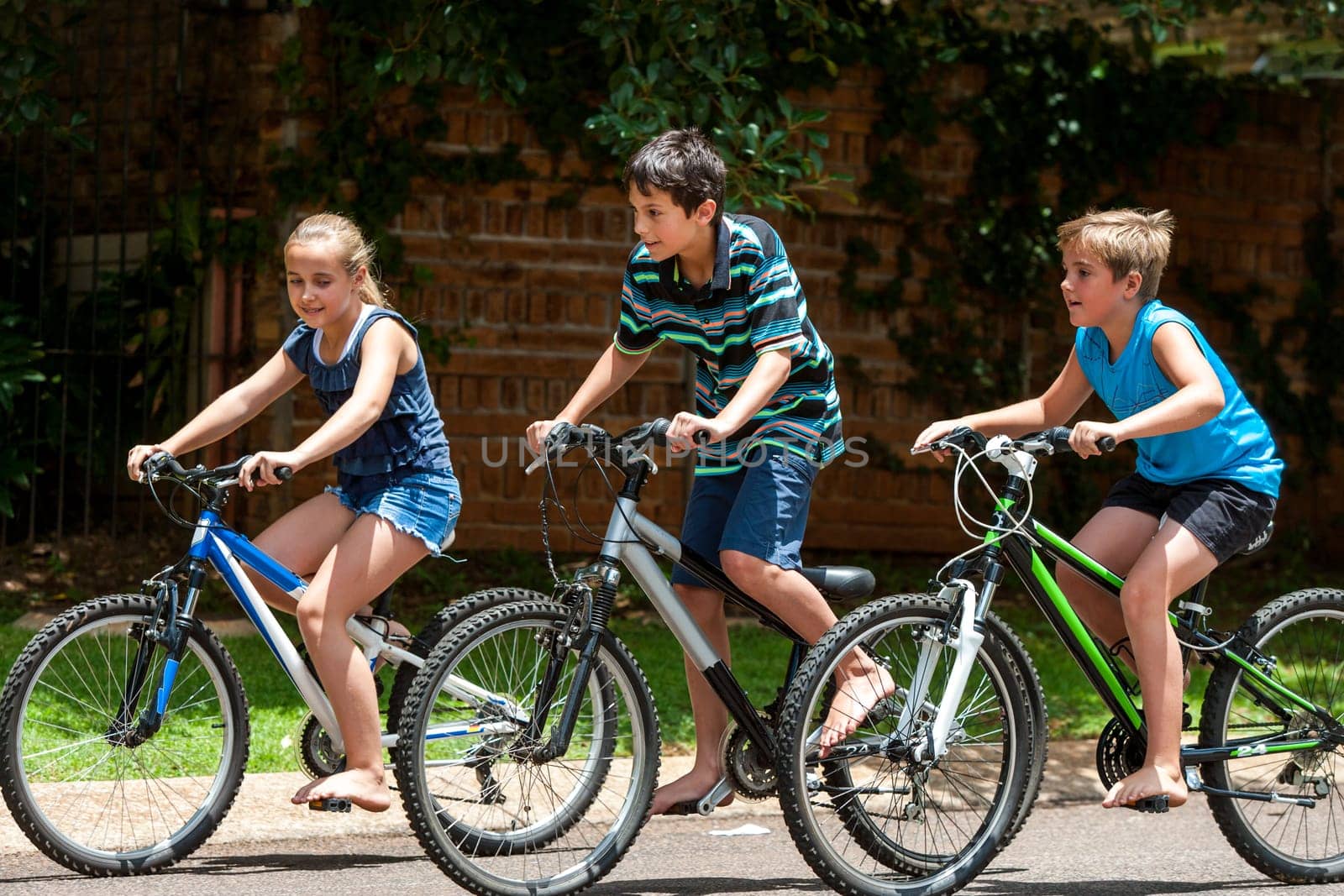 Motion shot of three kidscompeting with cycles outdoors.