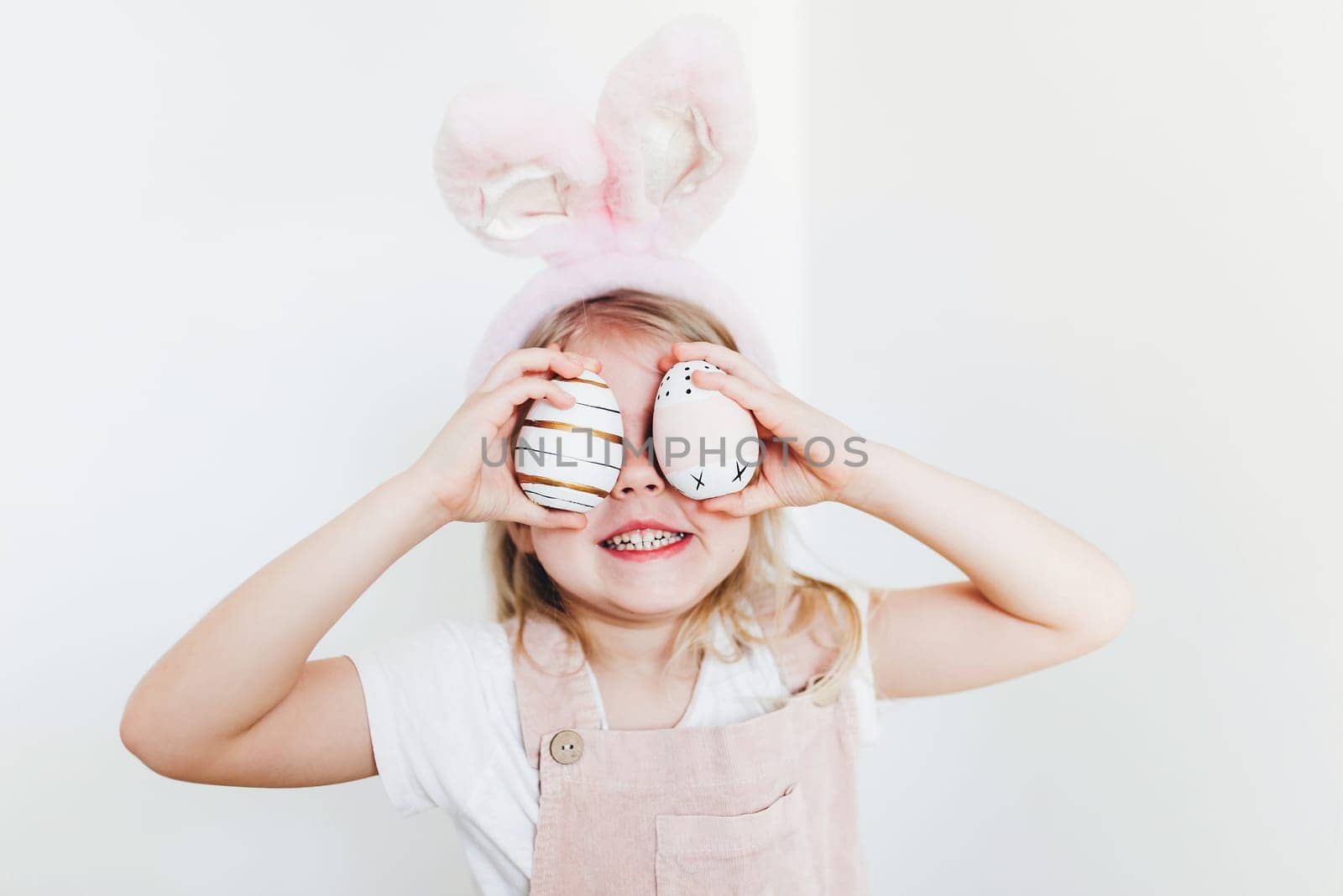 Little girl with Easter eggs and bunny ears hat. High quality photo