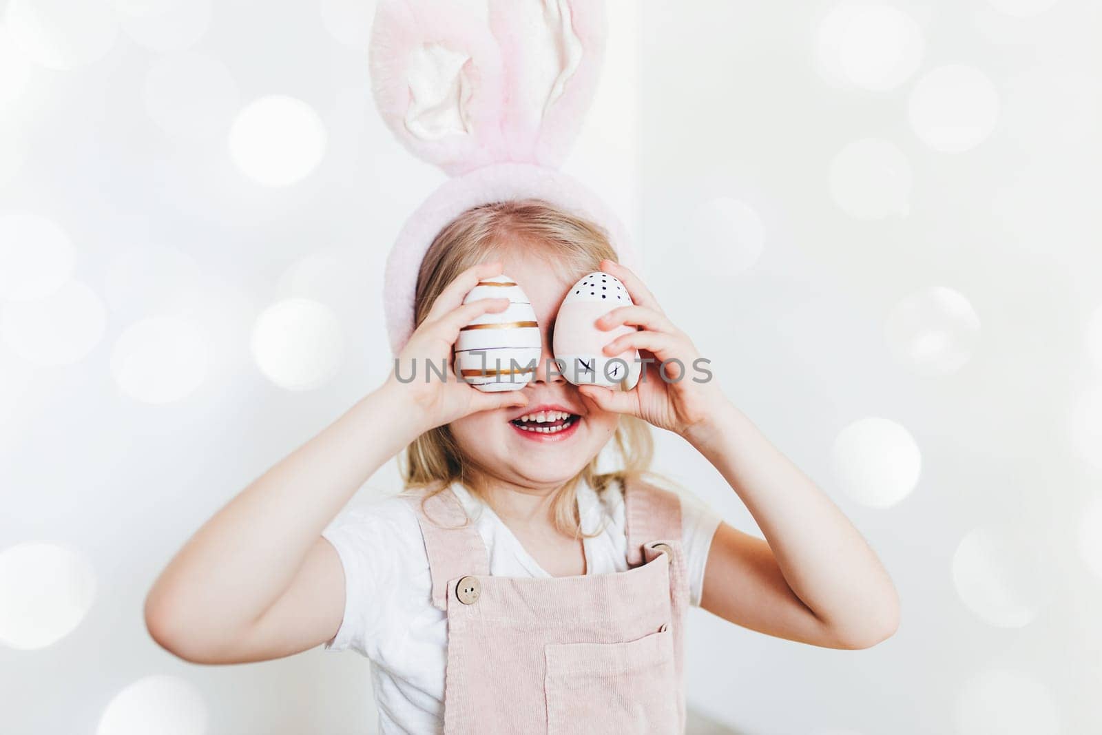 Little girl with Easter eggs and bunny ears hat. High quality photo