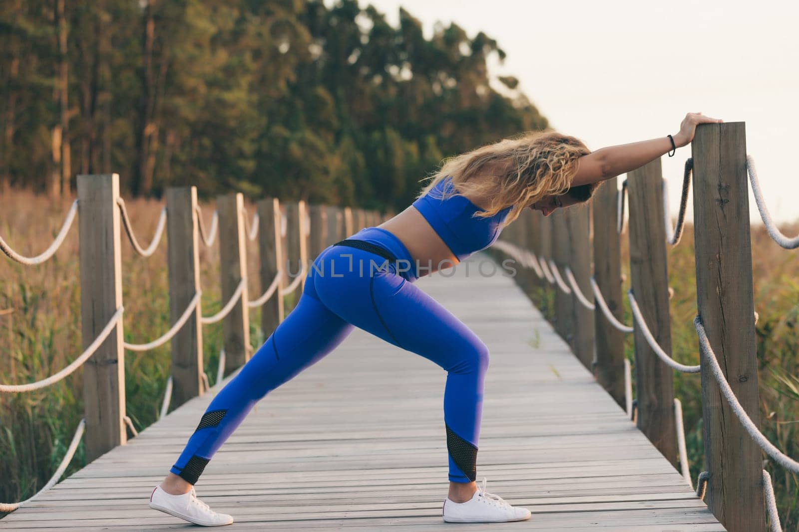 Young beautiful sportive girl exercising outdoors during sunrise/sunset