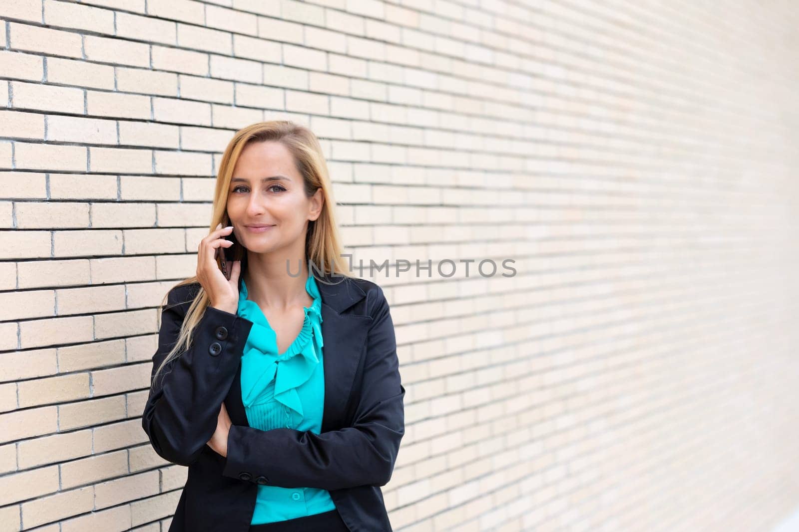 Successful businesswoman or entrepreneur talking on cellphone while outdoor. City business woman working.