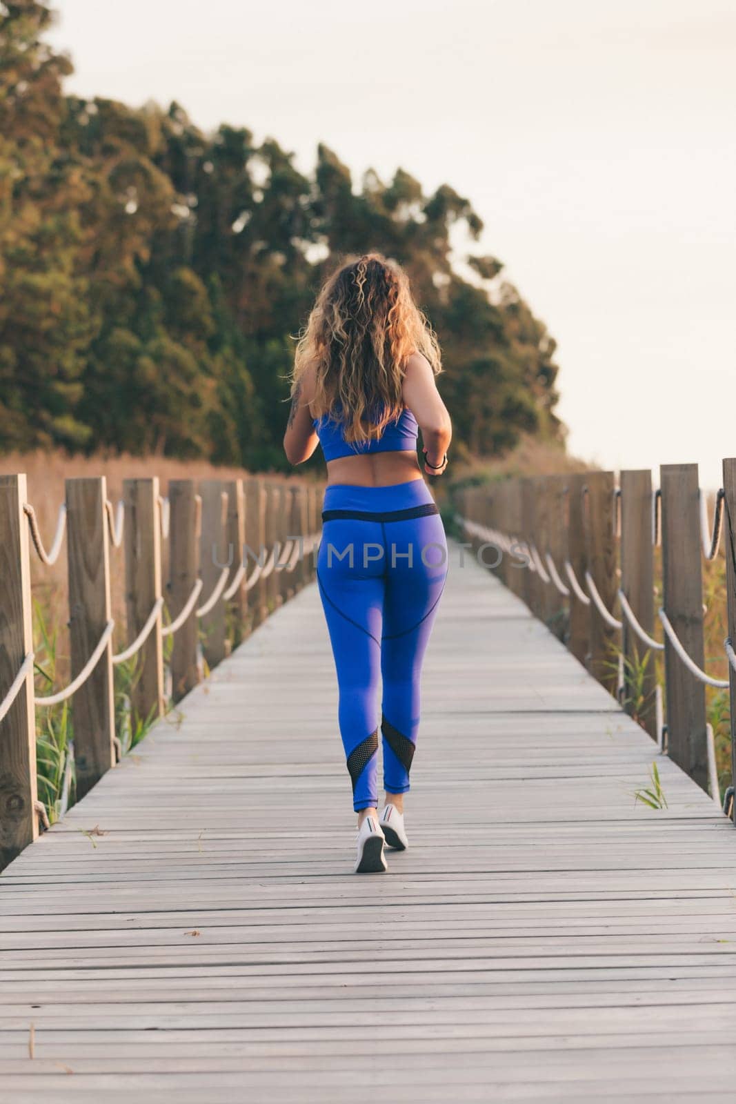 Young beautiful sportive girl exercising outdoors during sunrise/sunset