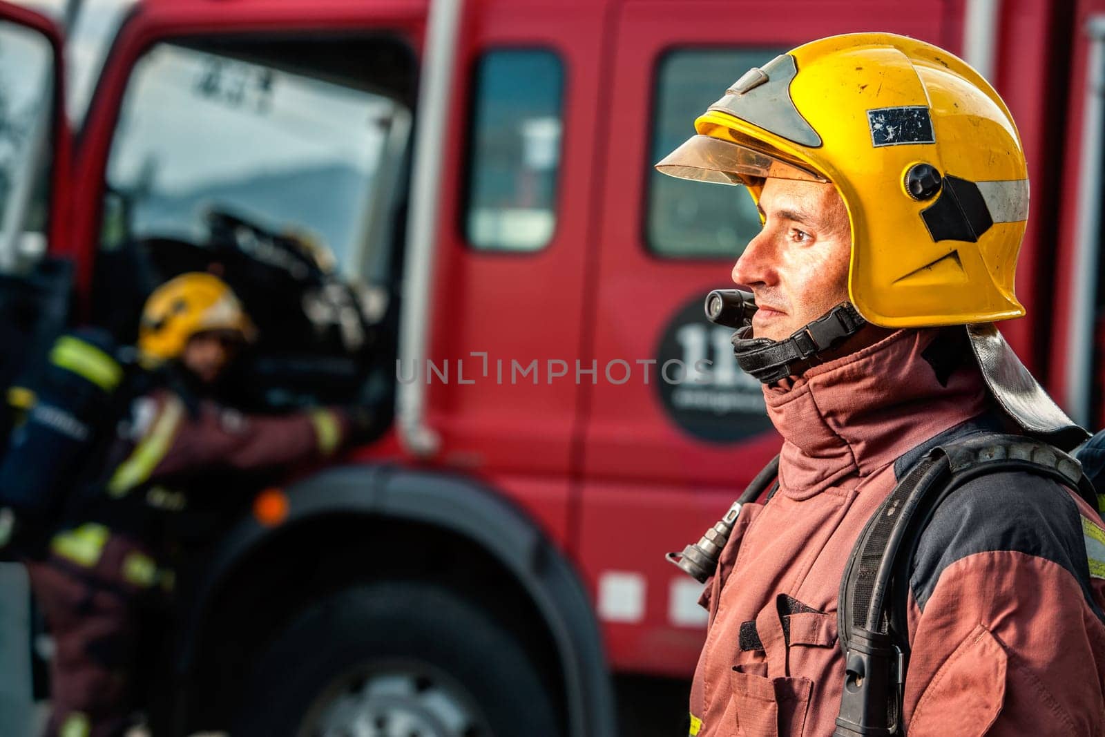 Close up portrait of Fireman staring at danger in front of fire truck.